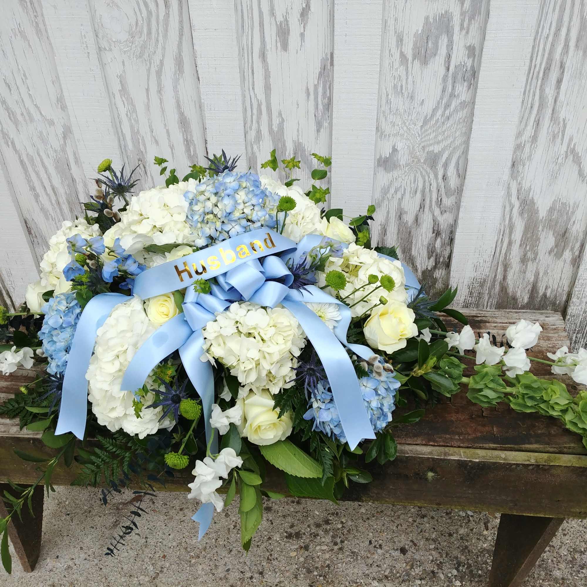 Blue and white floral arrangement with a ribbon reading Husband