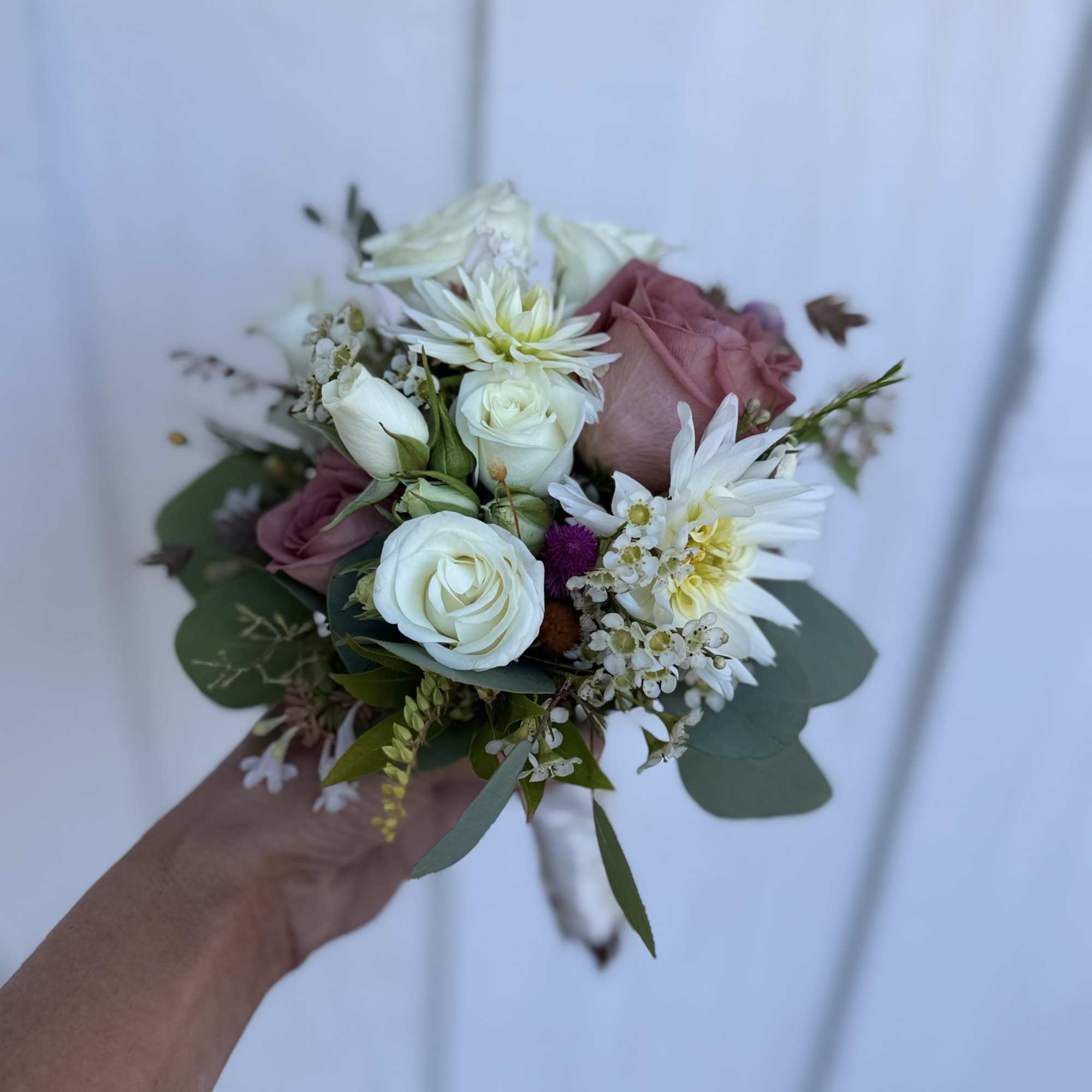 Handheld bouquet of white and blush roses with white daisies