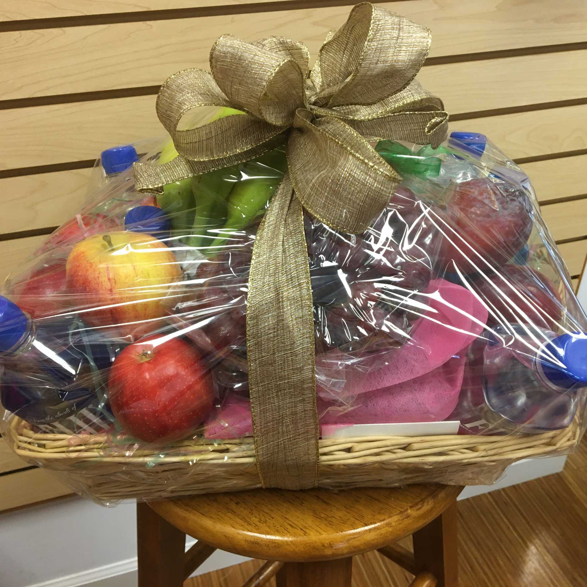 Gift basket of assorted fruit wrapped in plastic with a gold bow