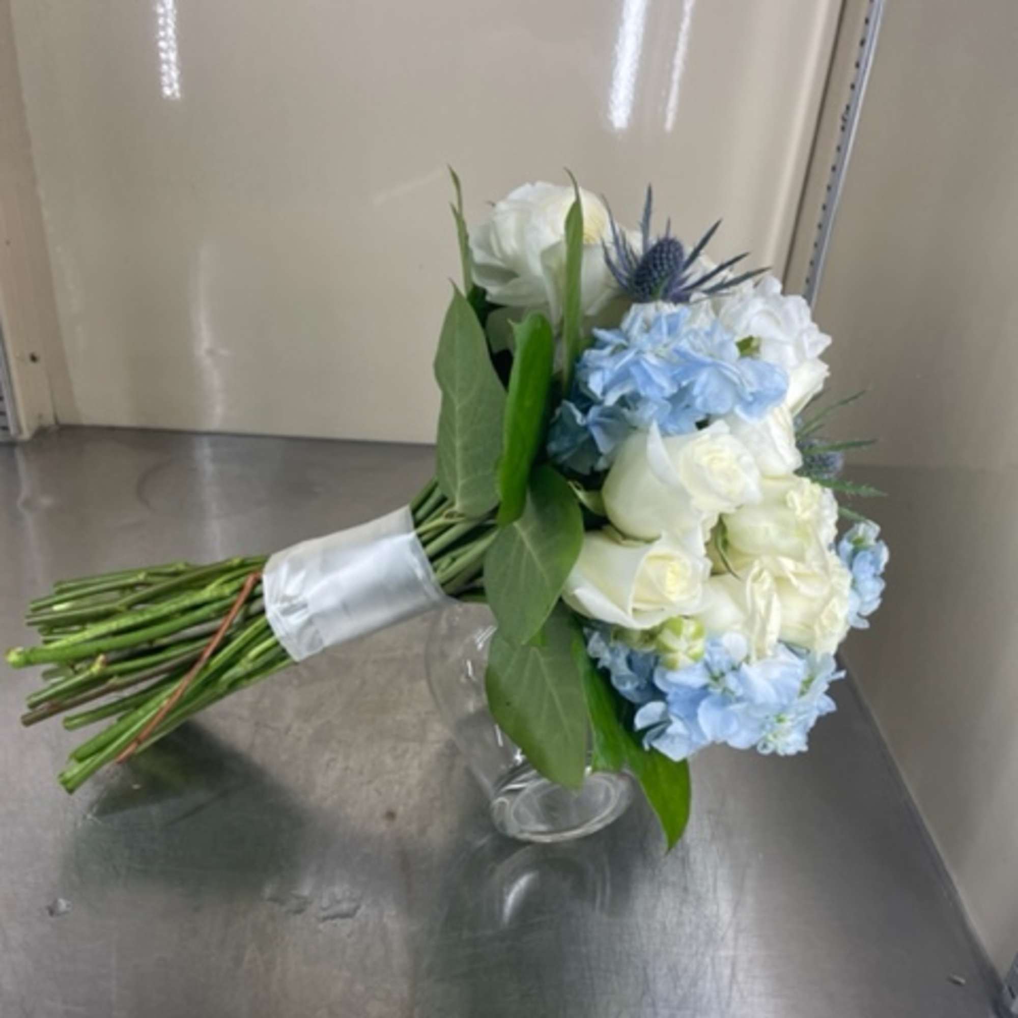 Bouquet of white and light blue flowers in a clear glass vase