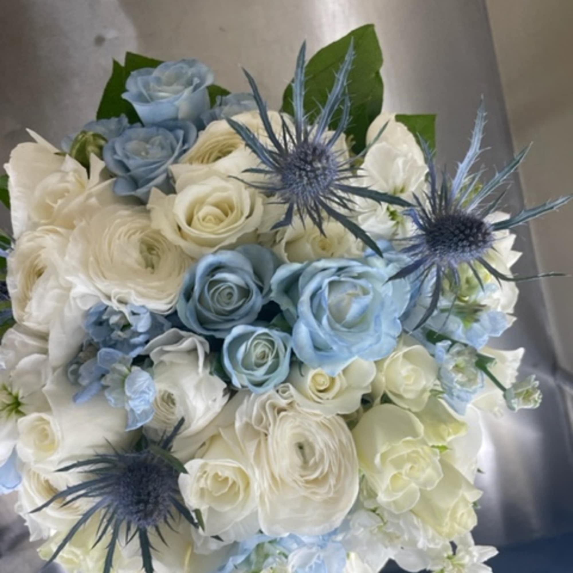Bouquet of white and pale blue roses with blue thistle flowers