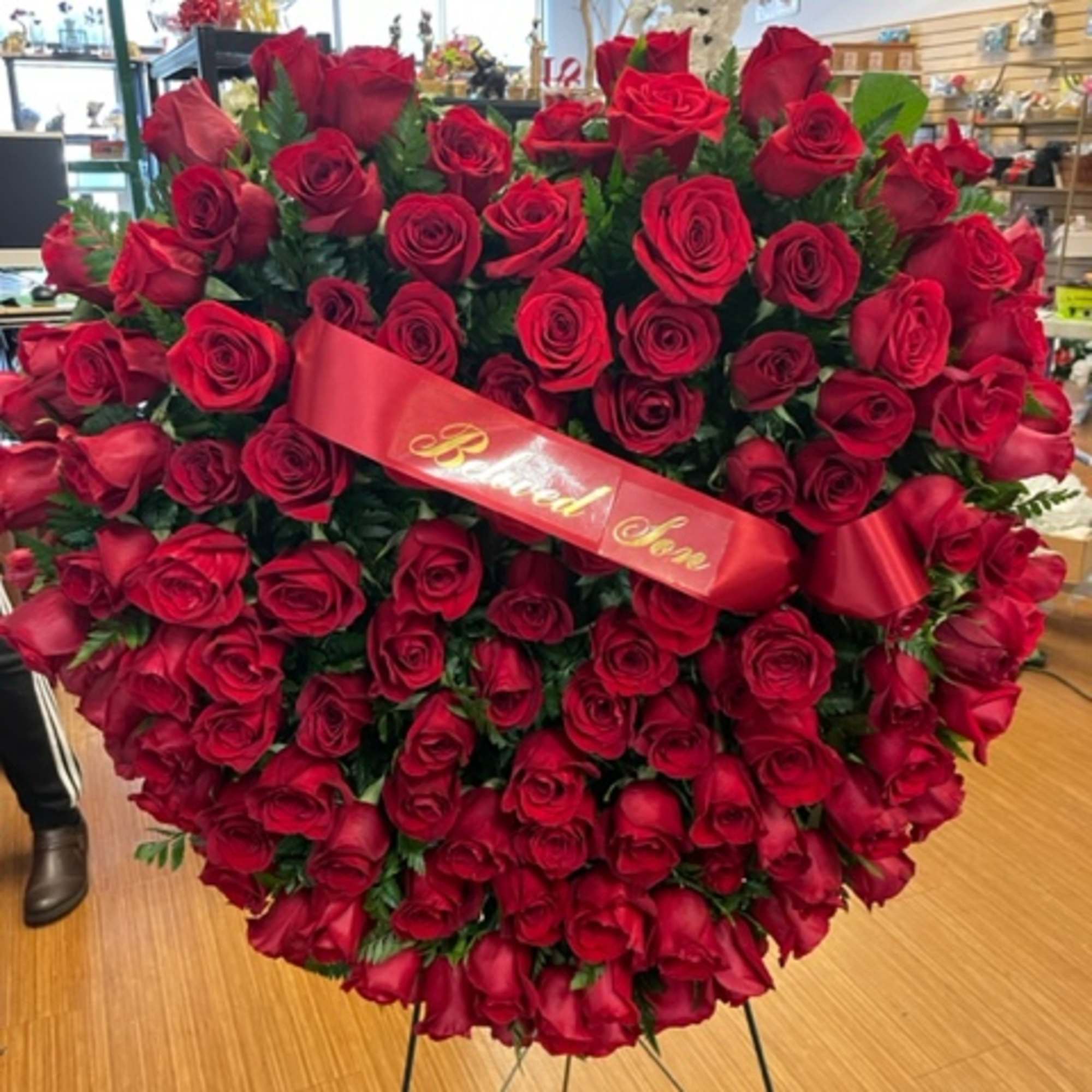 Large heart-shaped arrangement of red roses with a ribbon on an easel