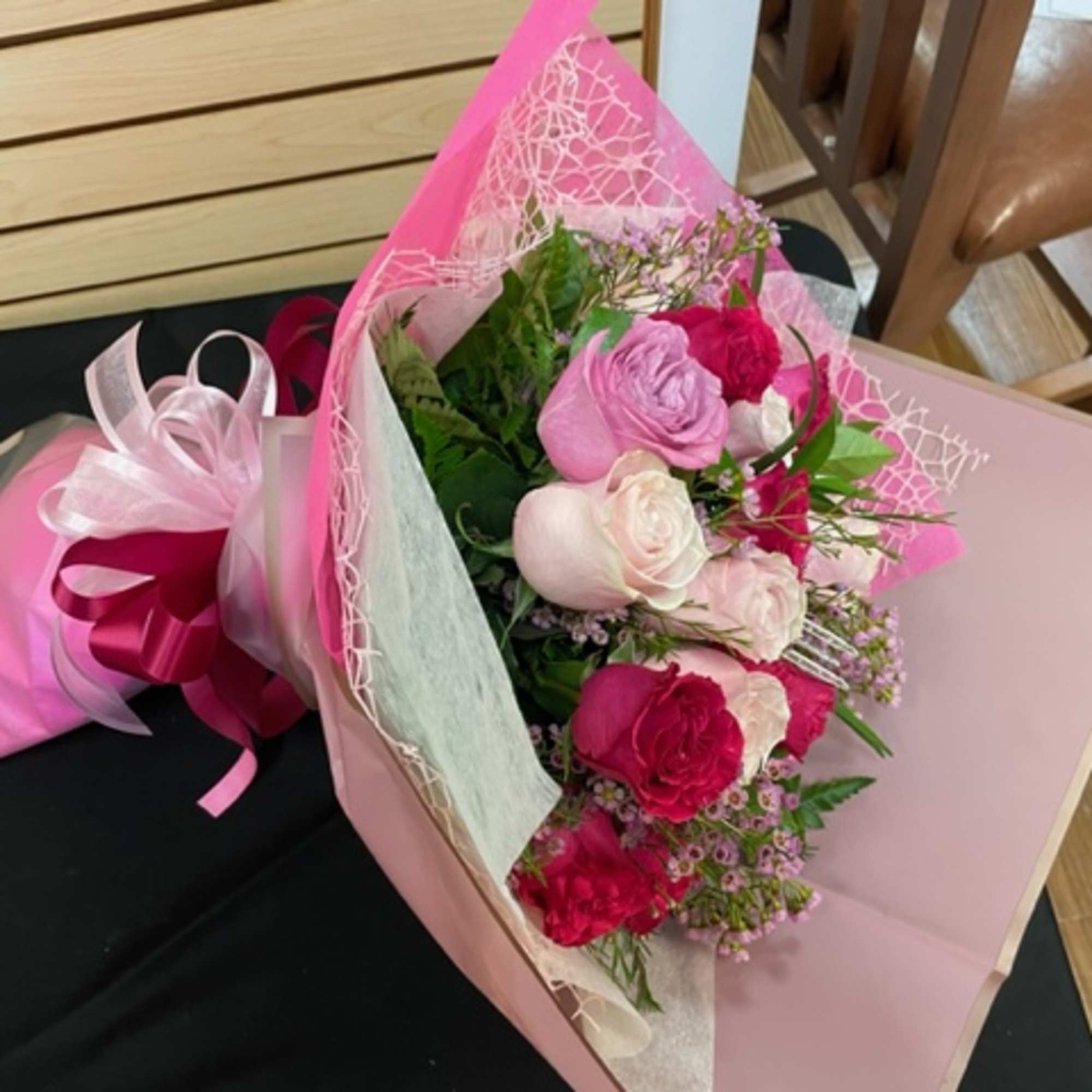 Pink and white rose bouquet wrapped in pink paper with ribbon