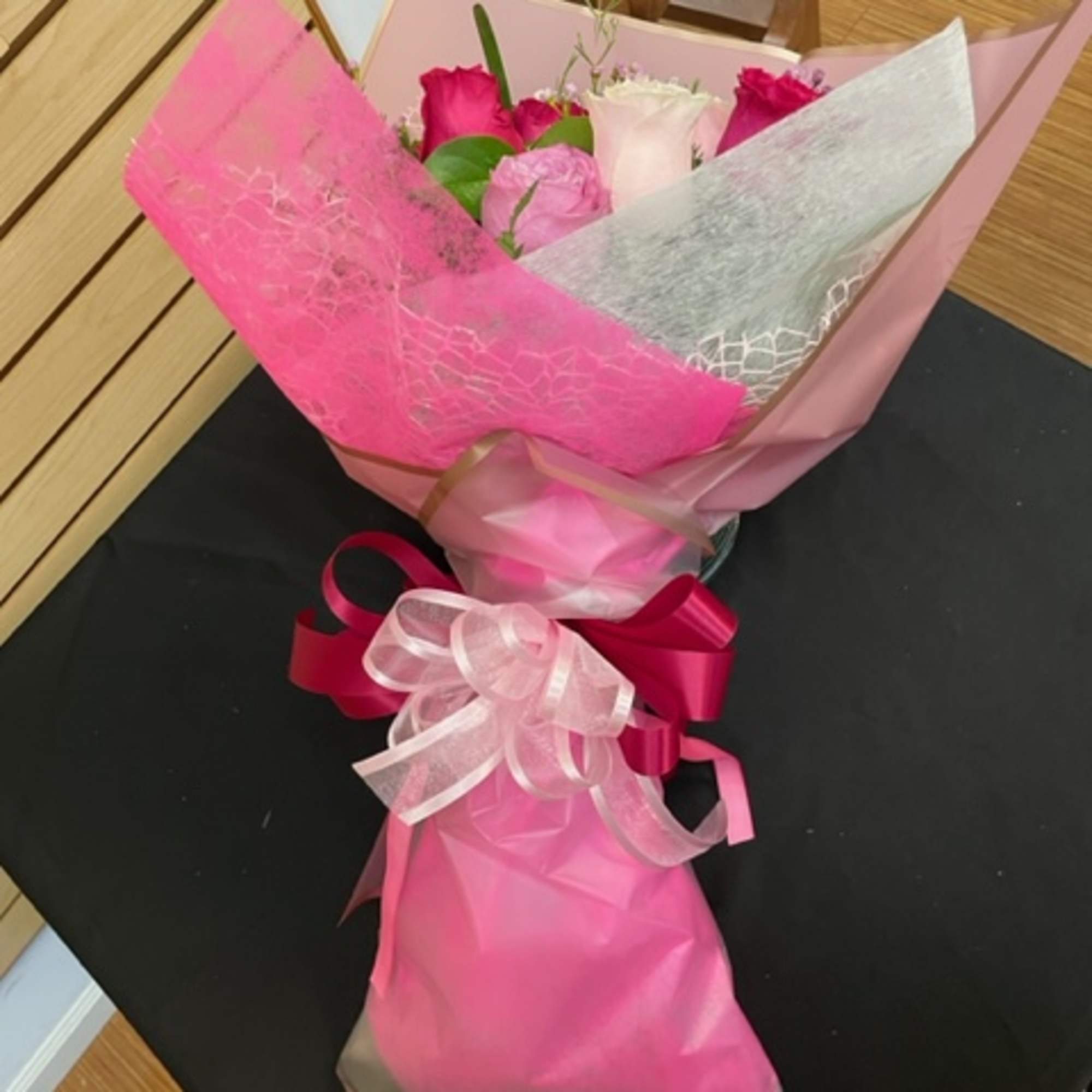 Bouquet of pink and white roses wrapped in pink paper with a ribbon
