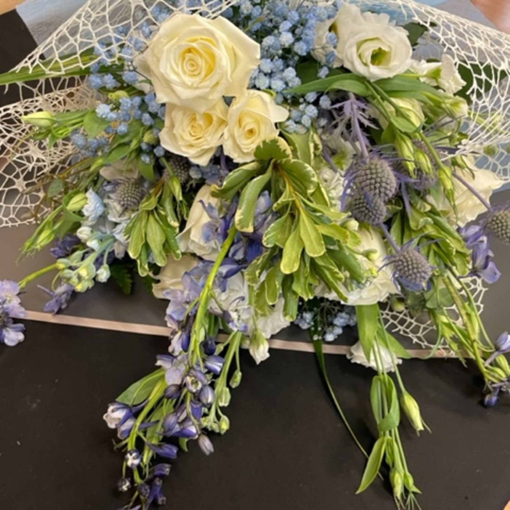 Bouquet of white roses and blue flowers with trailing greenery