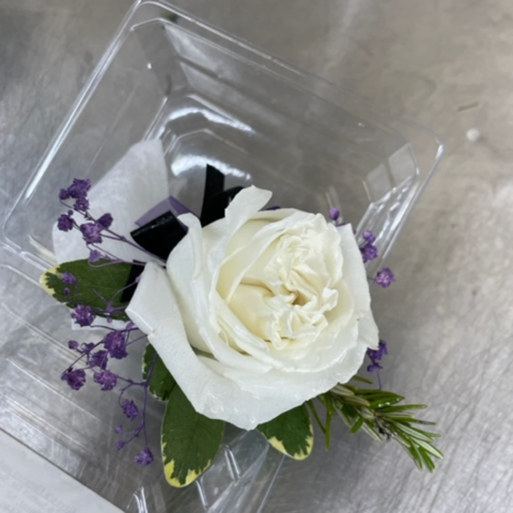White rose with purple filler in a clear plastic container