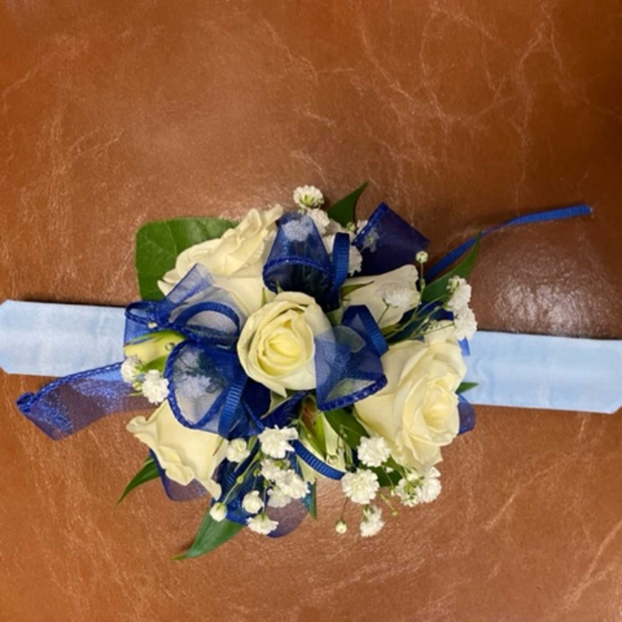 White rose wrist corsage with blue ribbon on a pale blue band