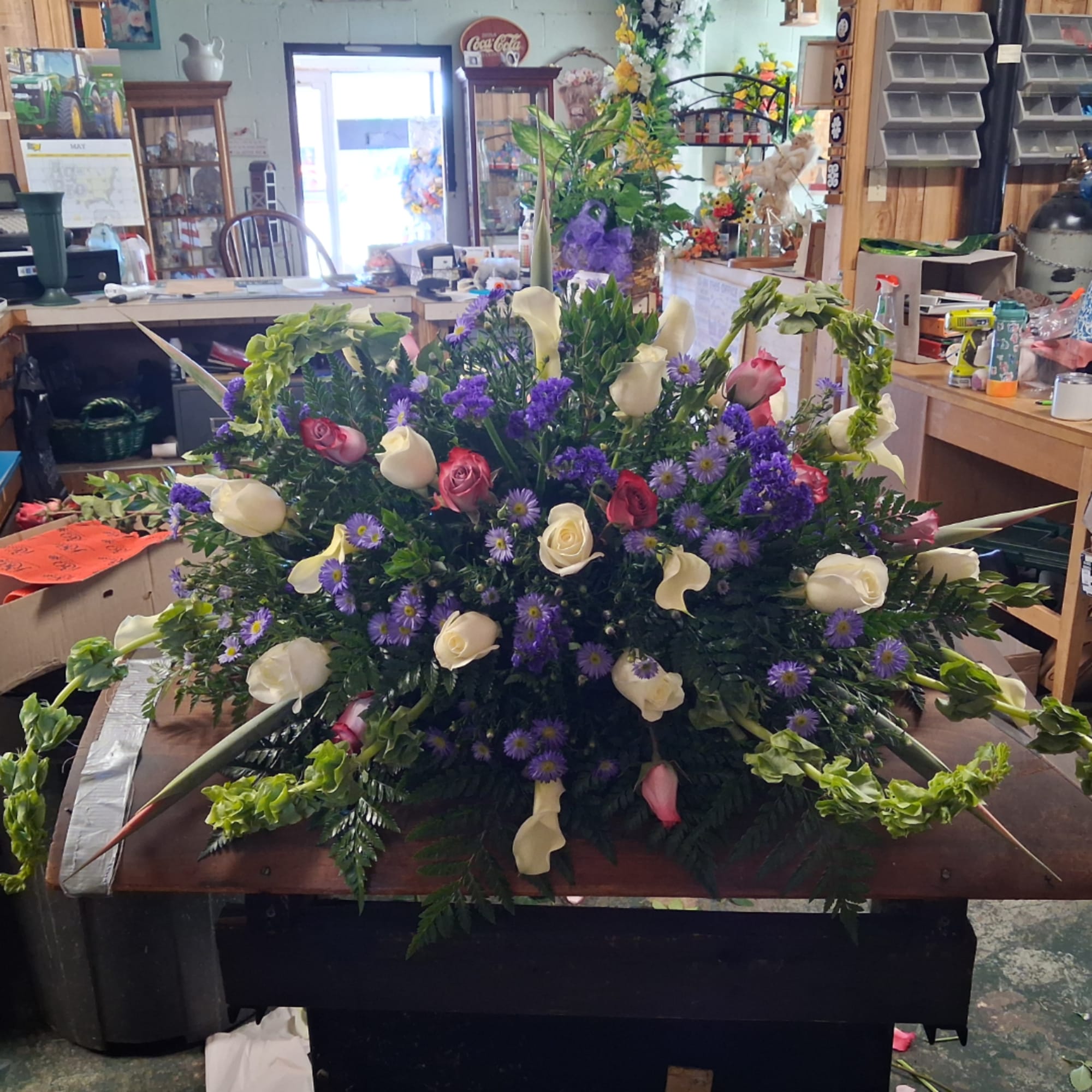 Large floral arrangement with white calla lilies, roses, and purple daisies