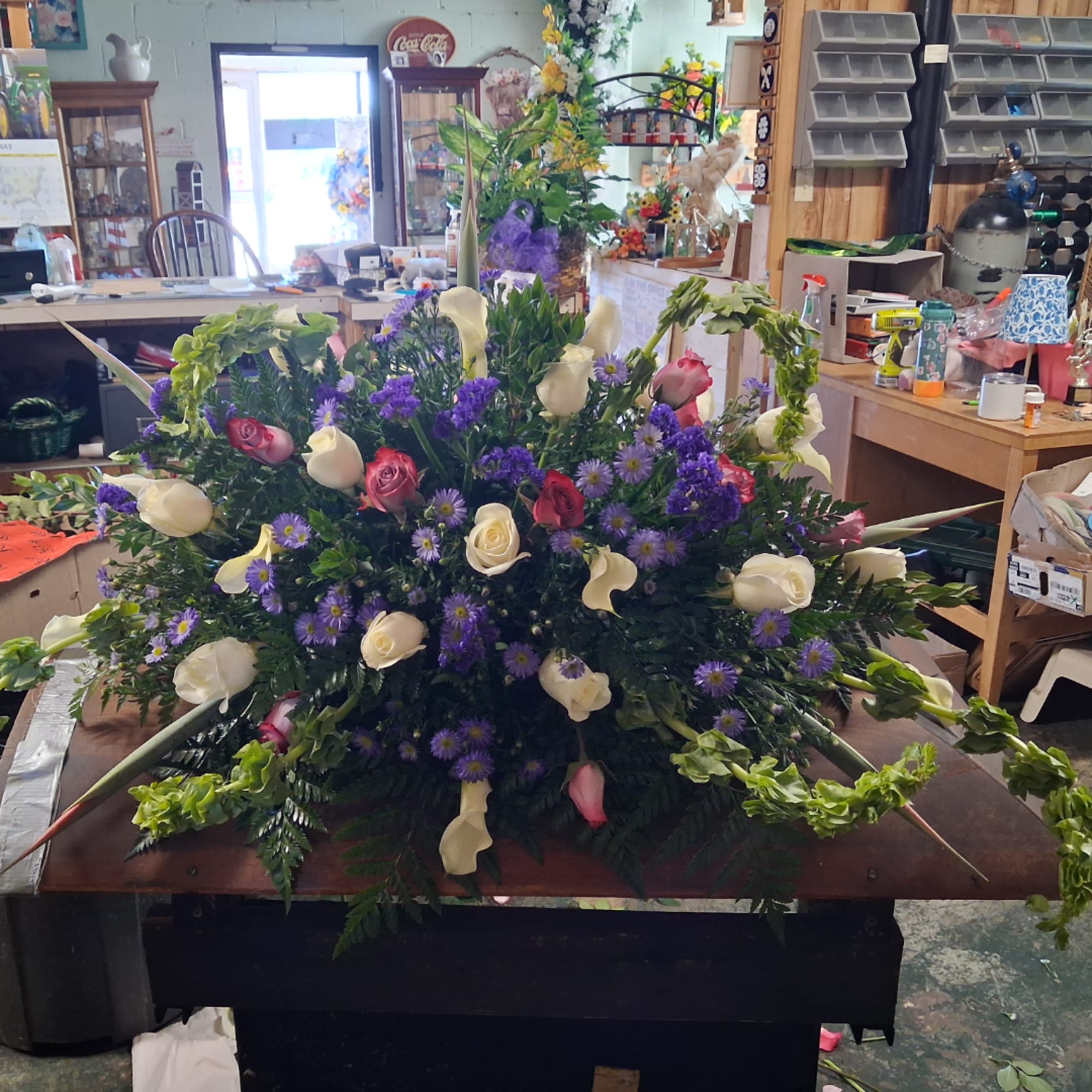 Large floral arrangement with white calla lilies, roses, and purple daisies