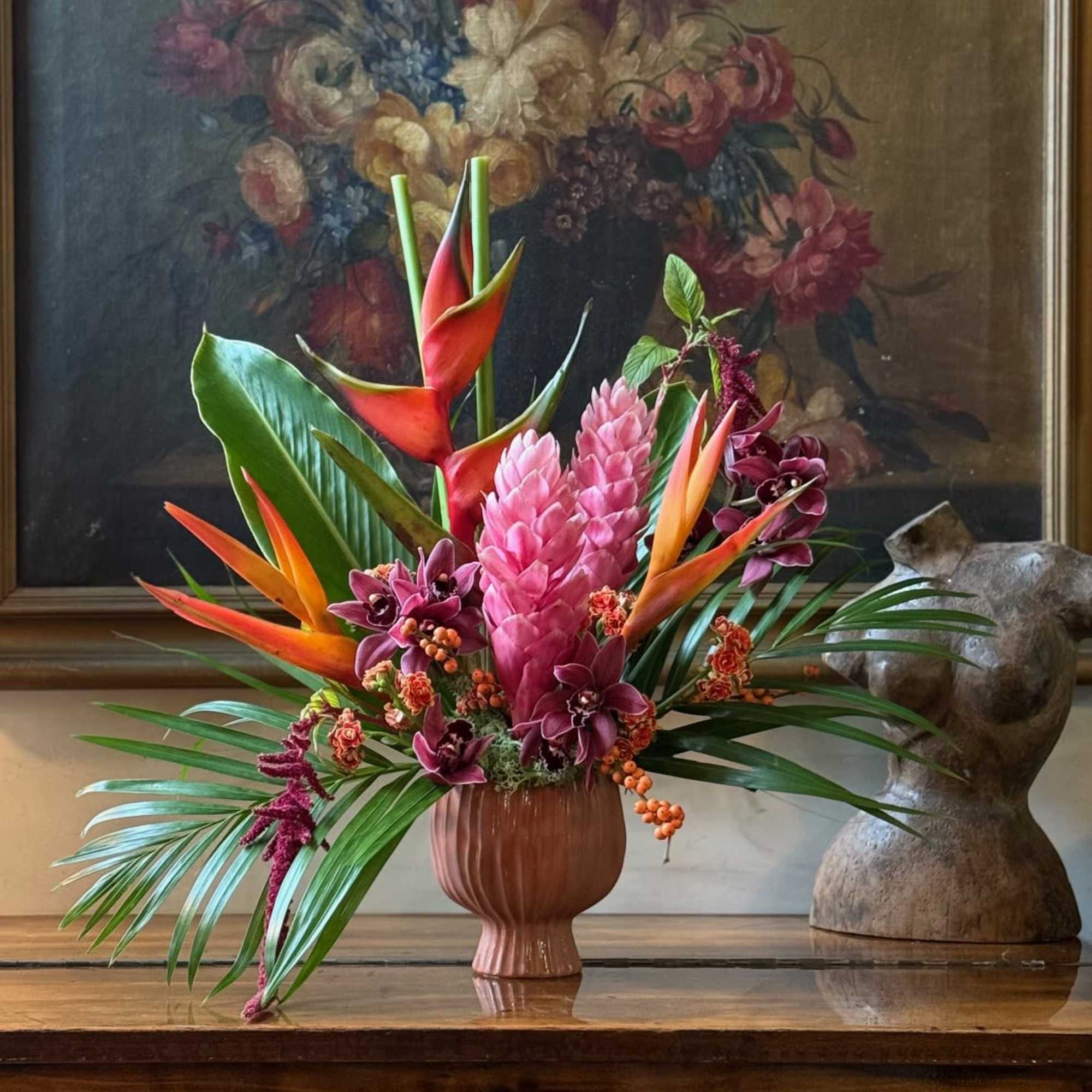 Tropical flower arrangement in a pink vase with orange and pink blooms