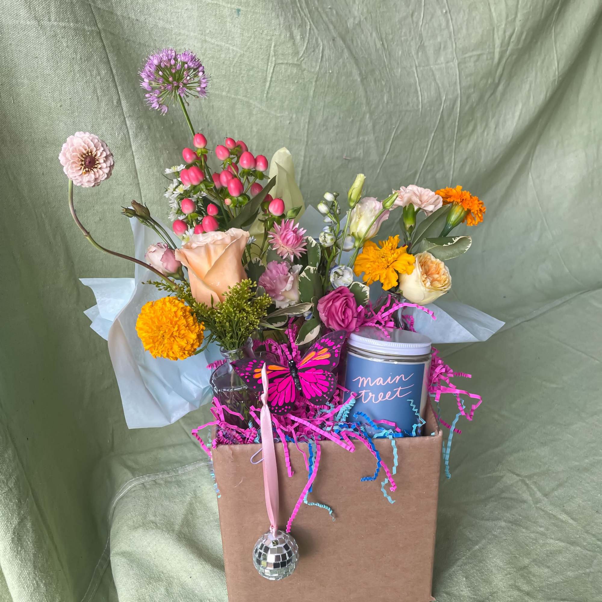 Mixed bouquet in a gift box with a candle and butterfly ornament