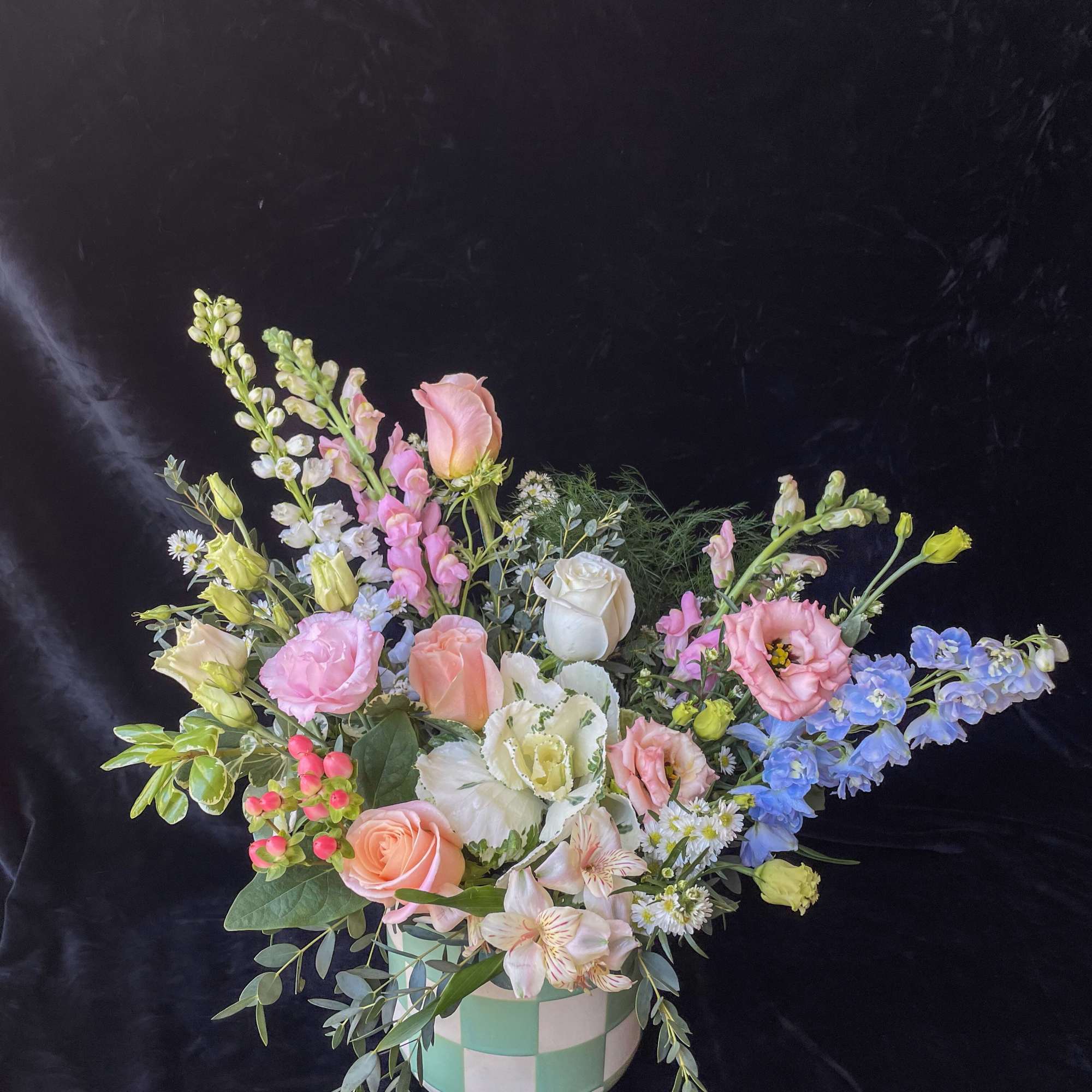 Pastel mixed flower arrangement in a checkered ceramic vase