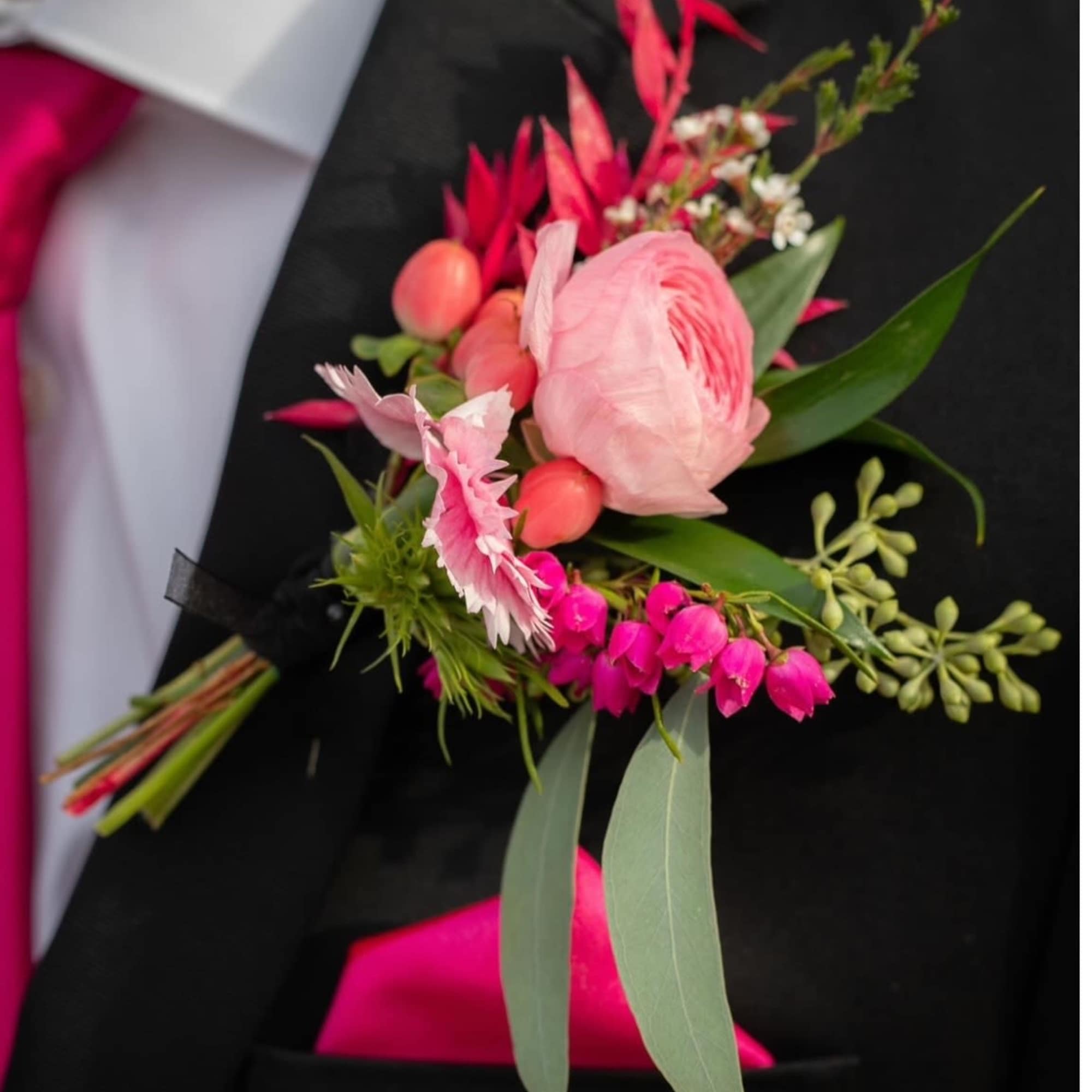 Pink boutonniere pinned to a black suit jacket