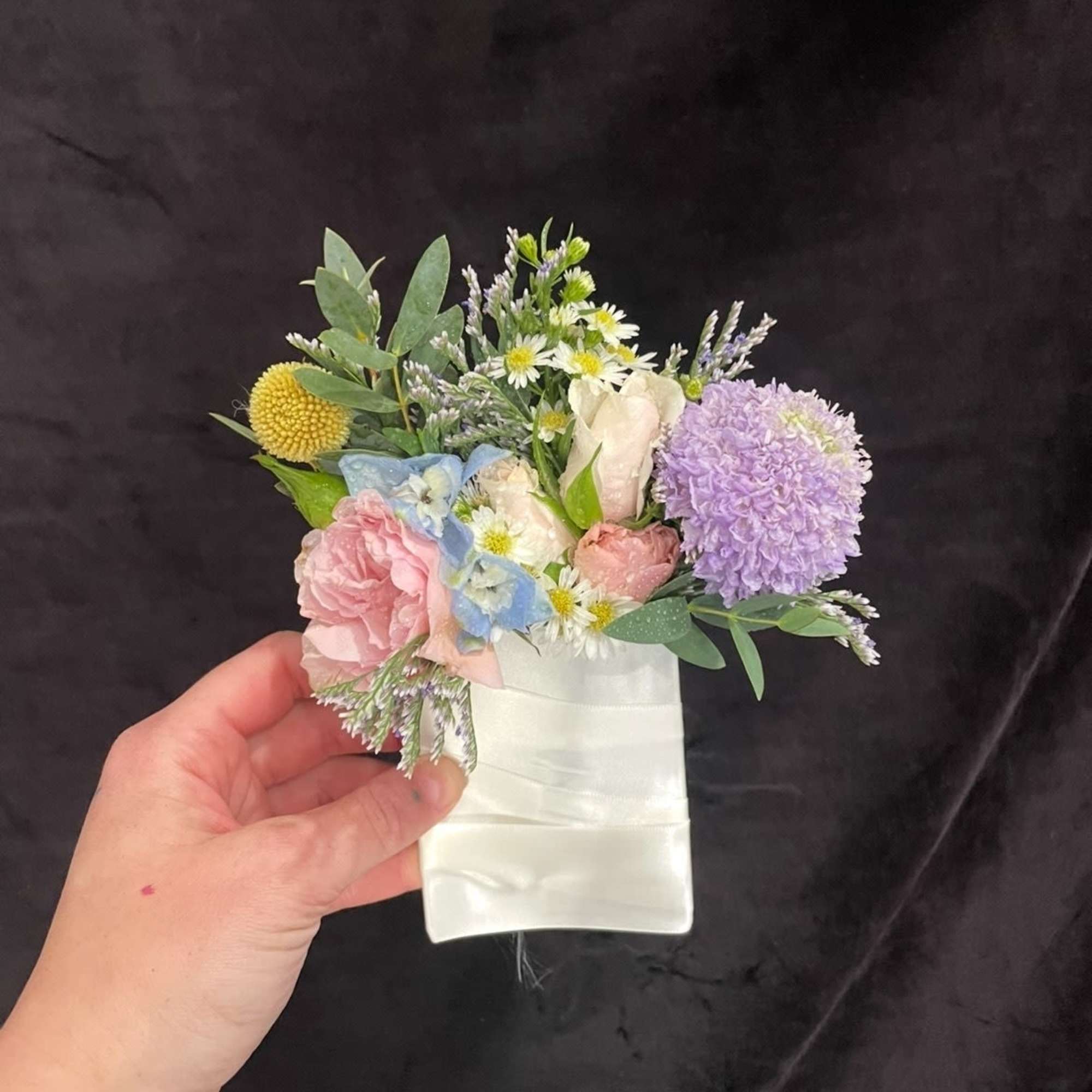 Small pastel bouquet with pink, lavender, and white flowers in a white wrap