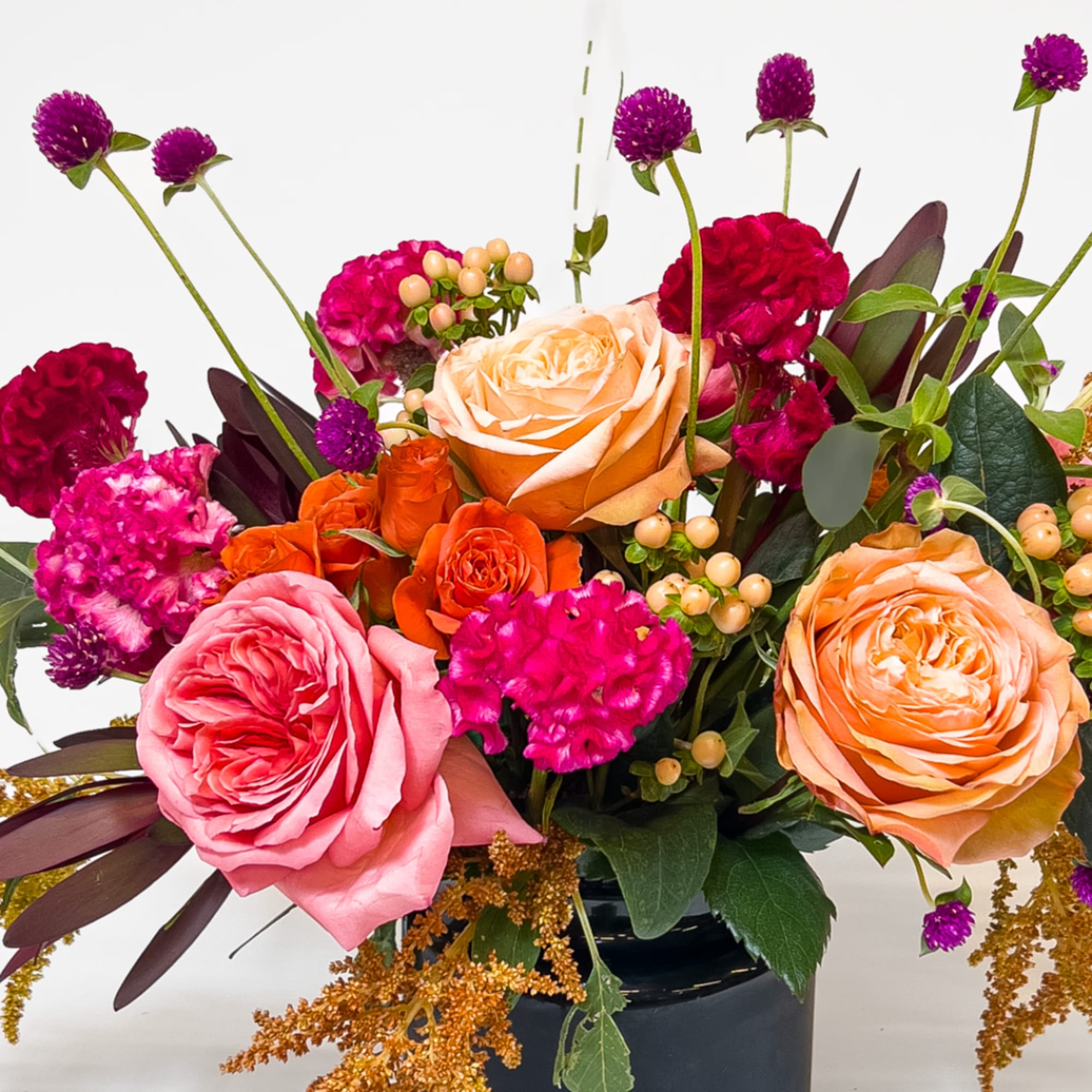 Mixed bouquet of roses and magenta flowers in a dark vase