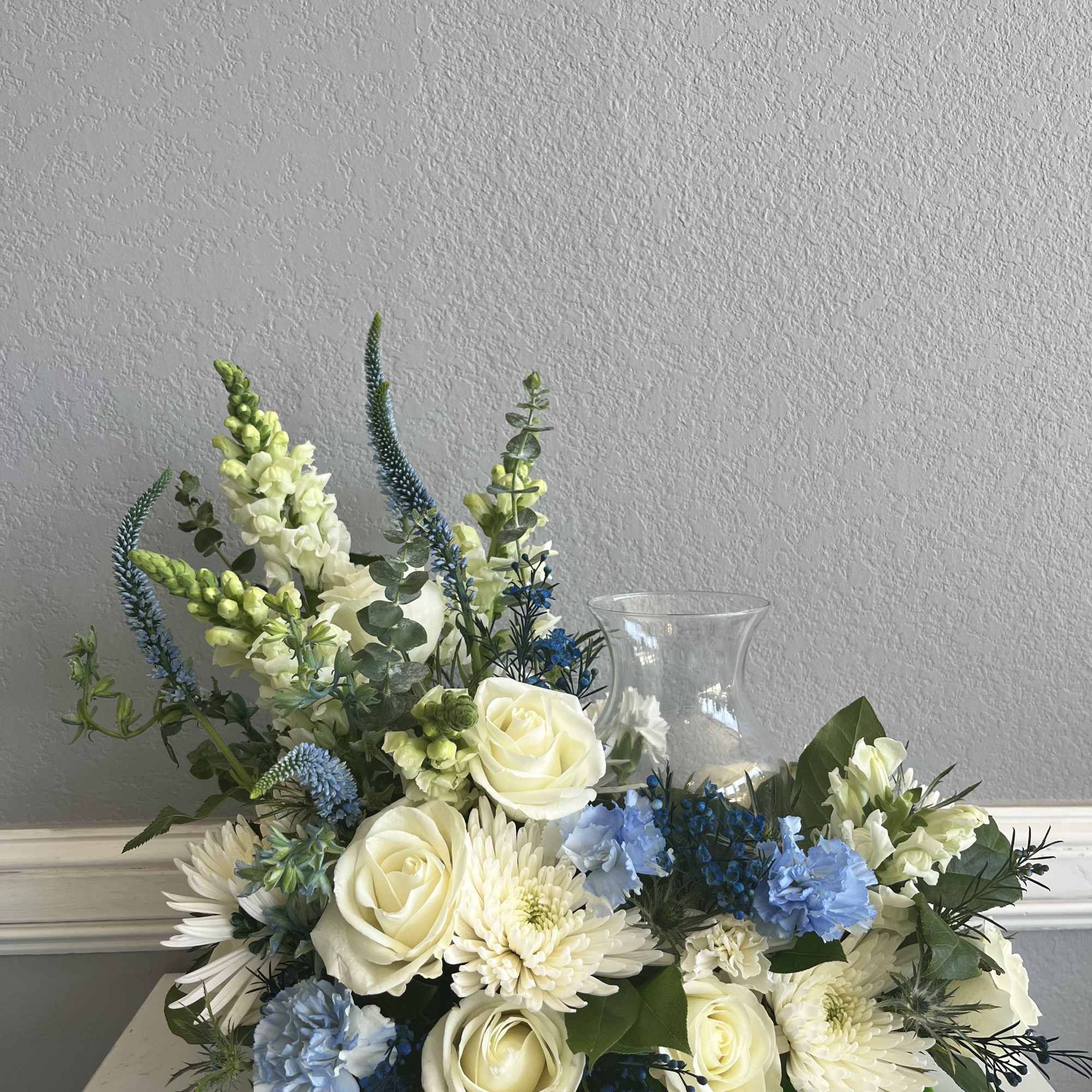 White and blue floral arrangement in a clear glass vase