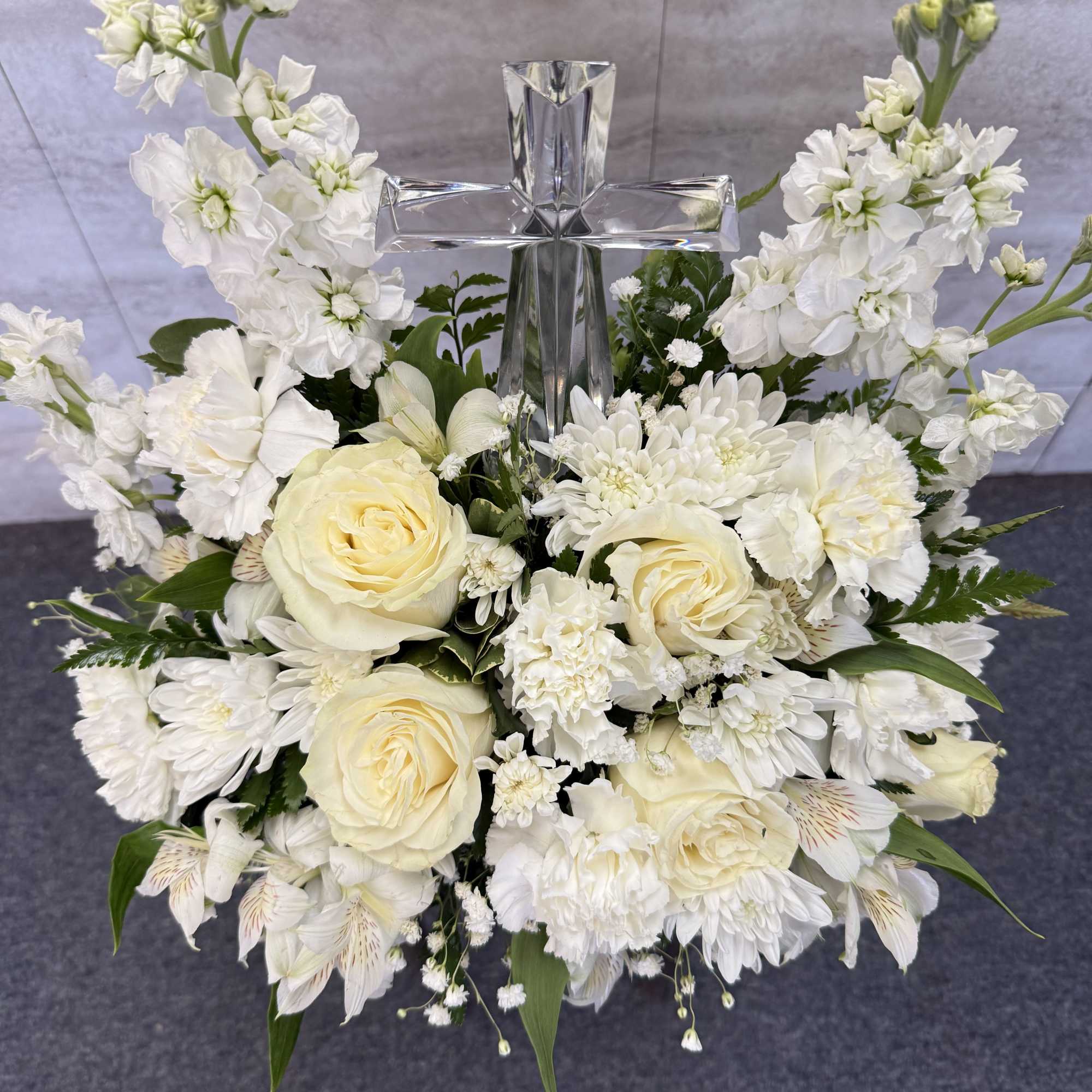 White floral arrangement with a clear glass cross centerpiece