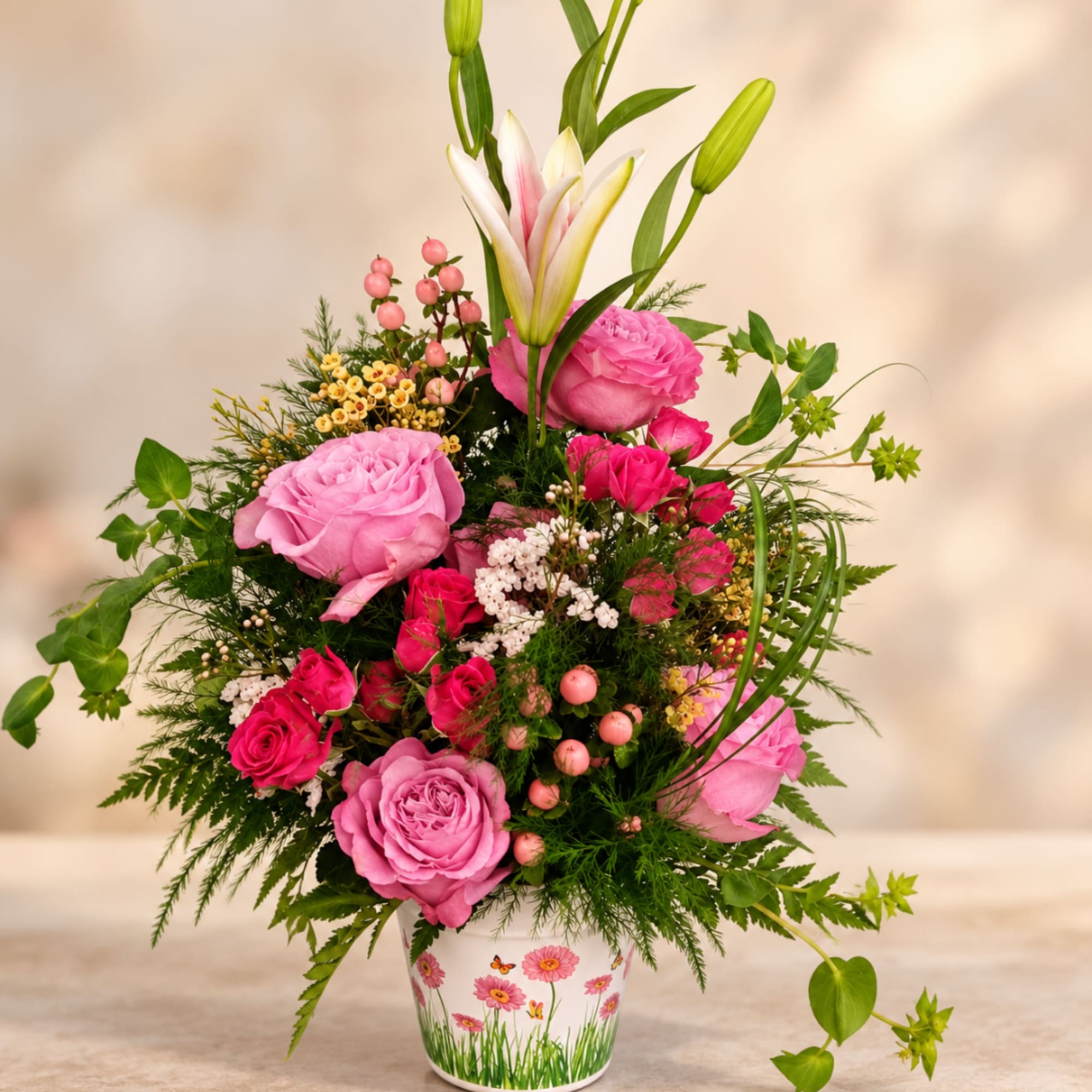 Pink roses and lilies arranged in a decorated white pot