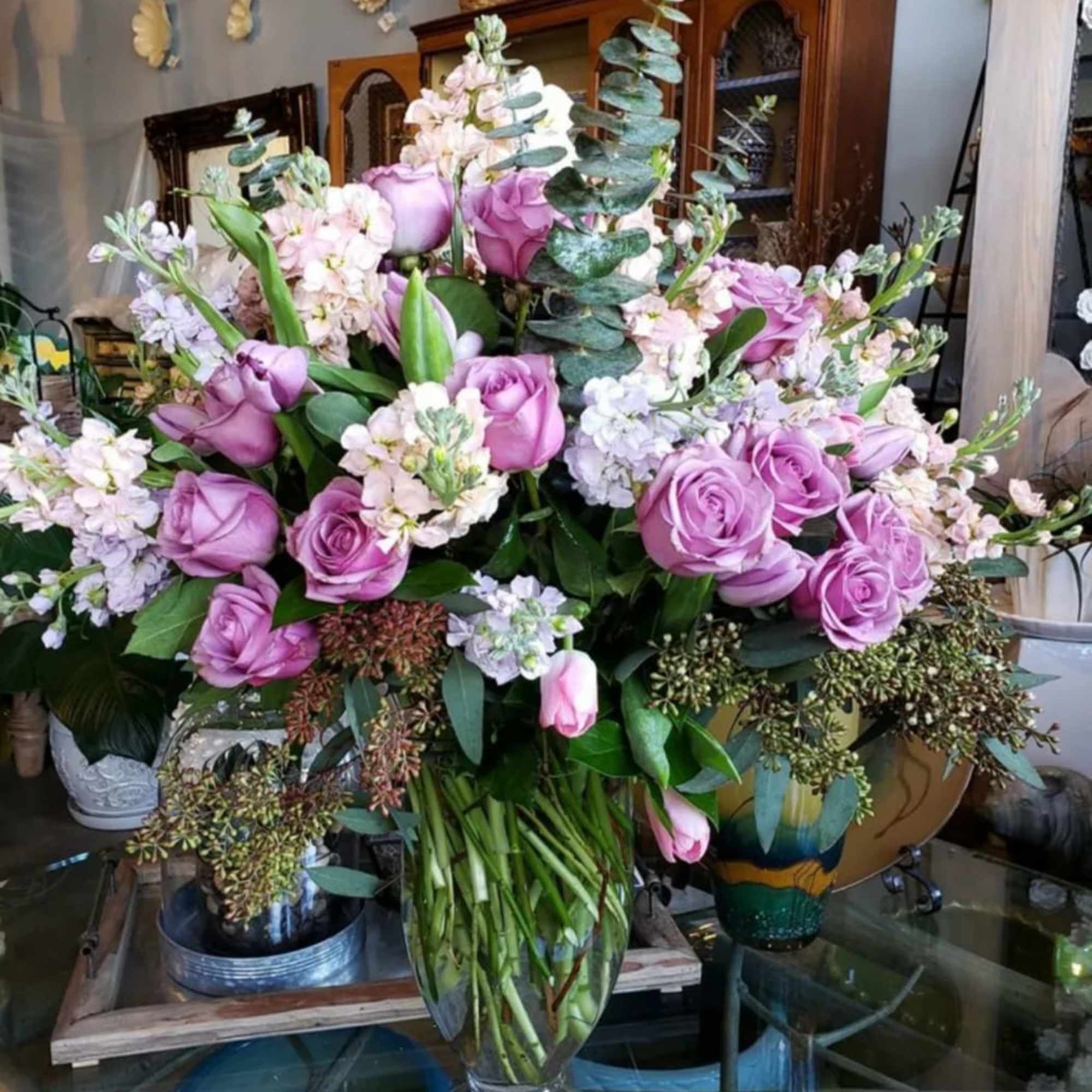 Lavender roses and pale pink flowers arranged in a clear glass vase, photo 3 of 3