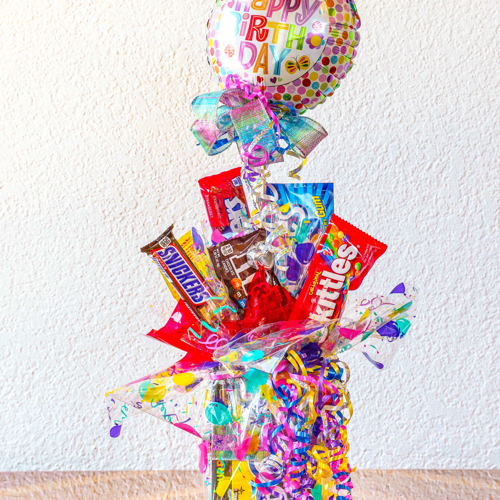 Birthday balloon and candy gift arrangement with colorful ribbons