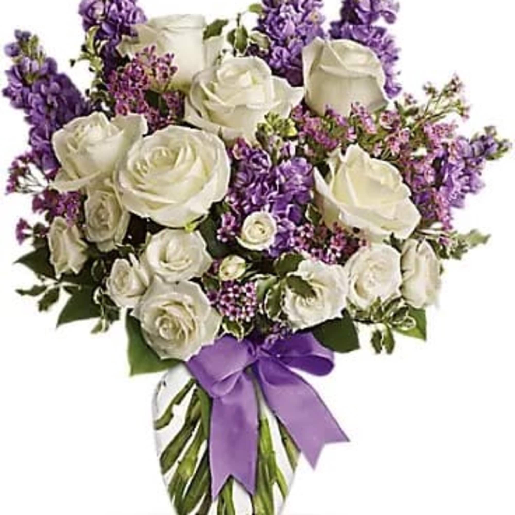 White roses and purple flowers in a glass vase with a purple ribbon