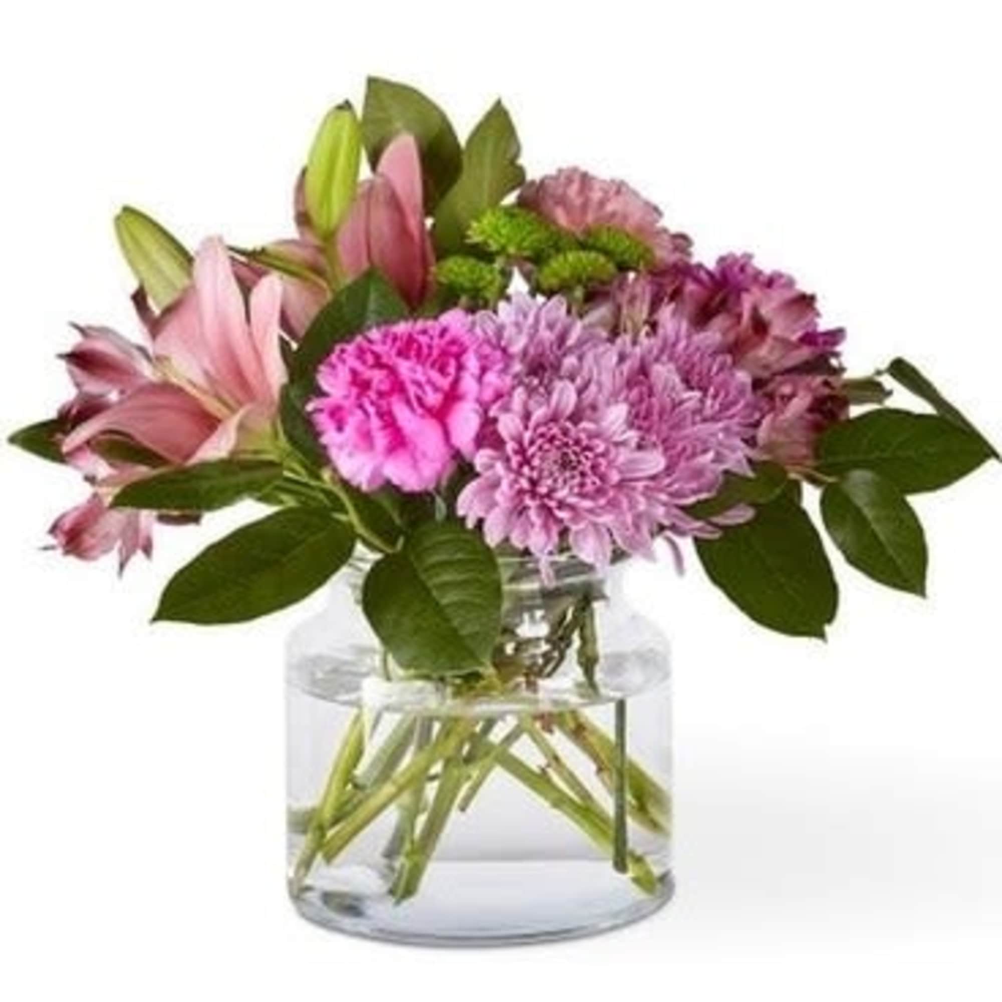 Pink lilies and purple flowers in a clear glass vase