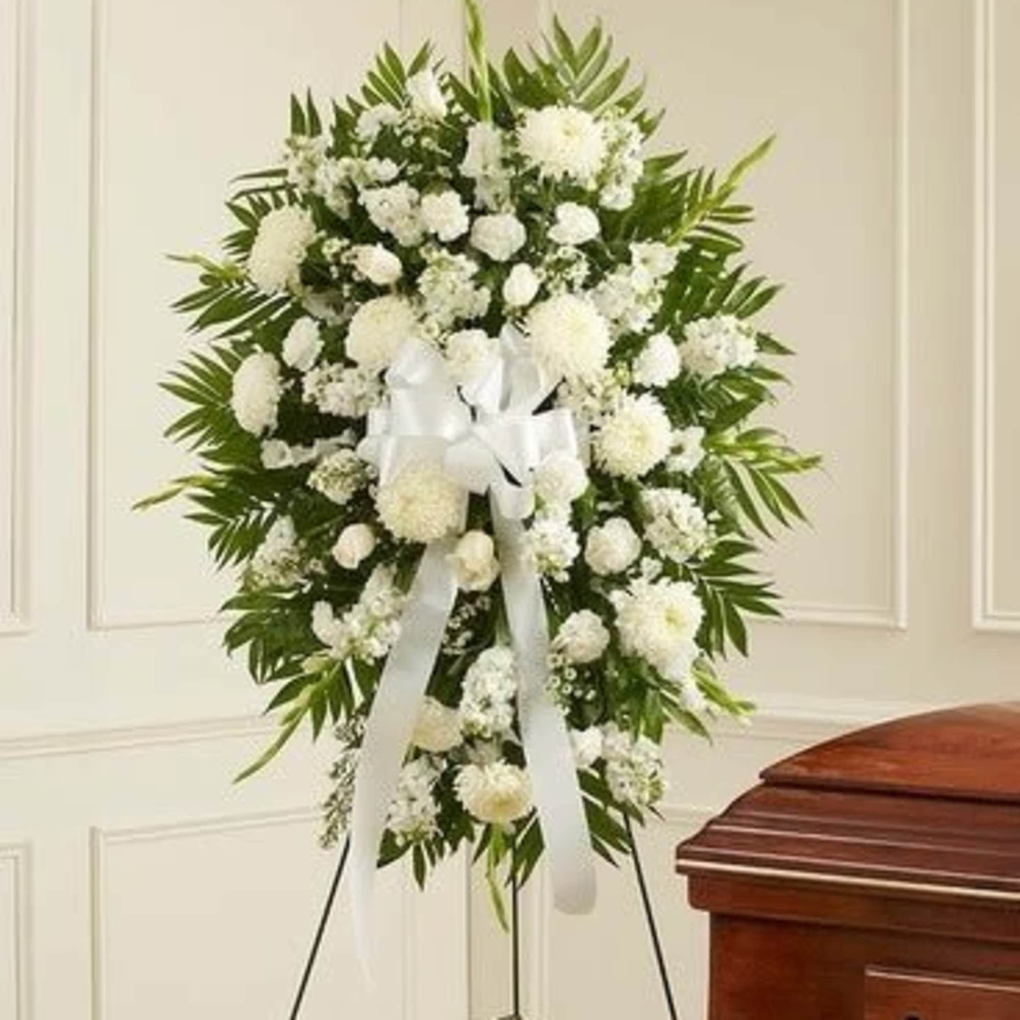 White funeral wreath on a stand with a ribbon bow