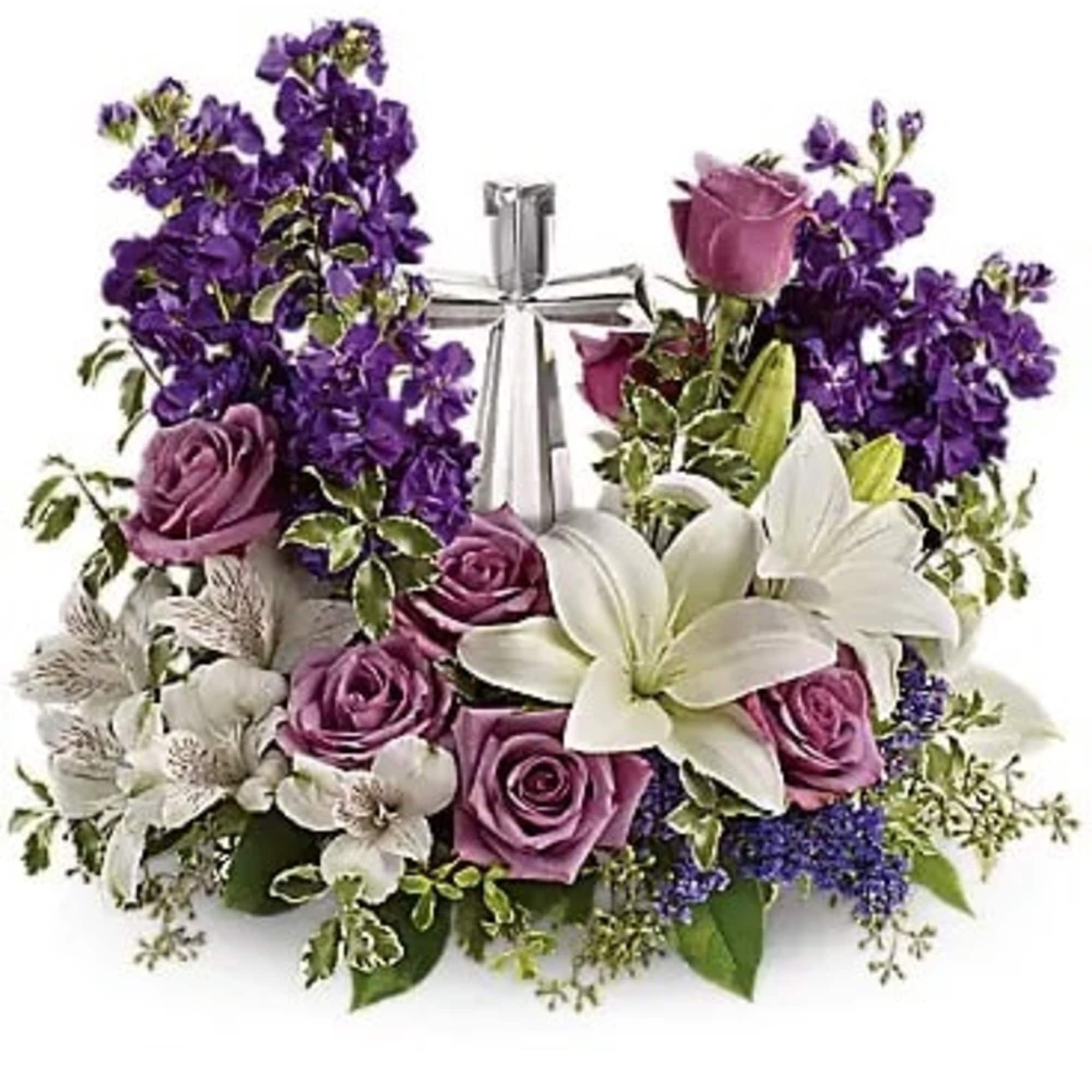 Purple roses and white lilies arranged around a silver cross
