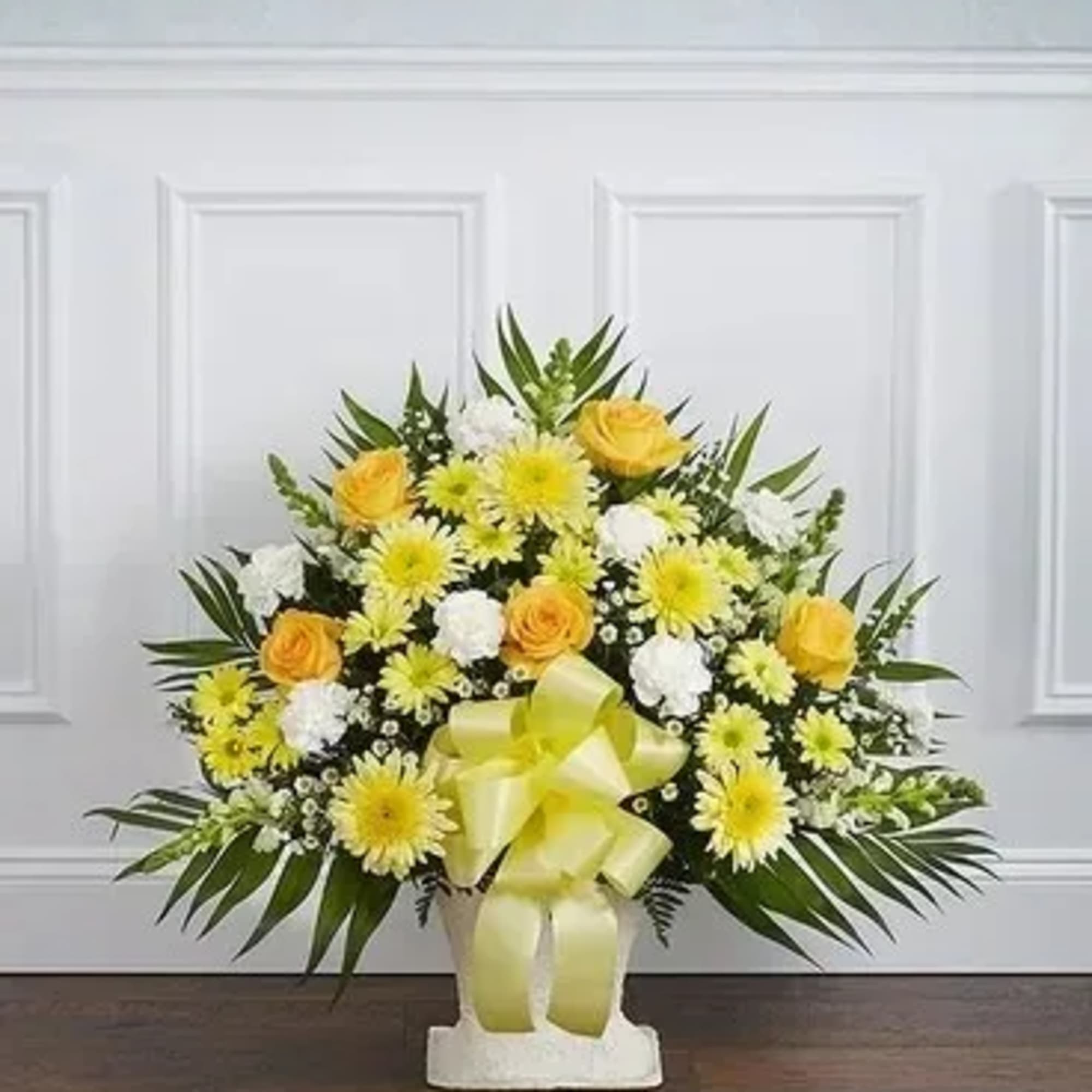 Yellow and white floral arrangement in a white vase with a ribbon