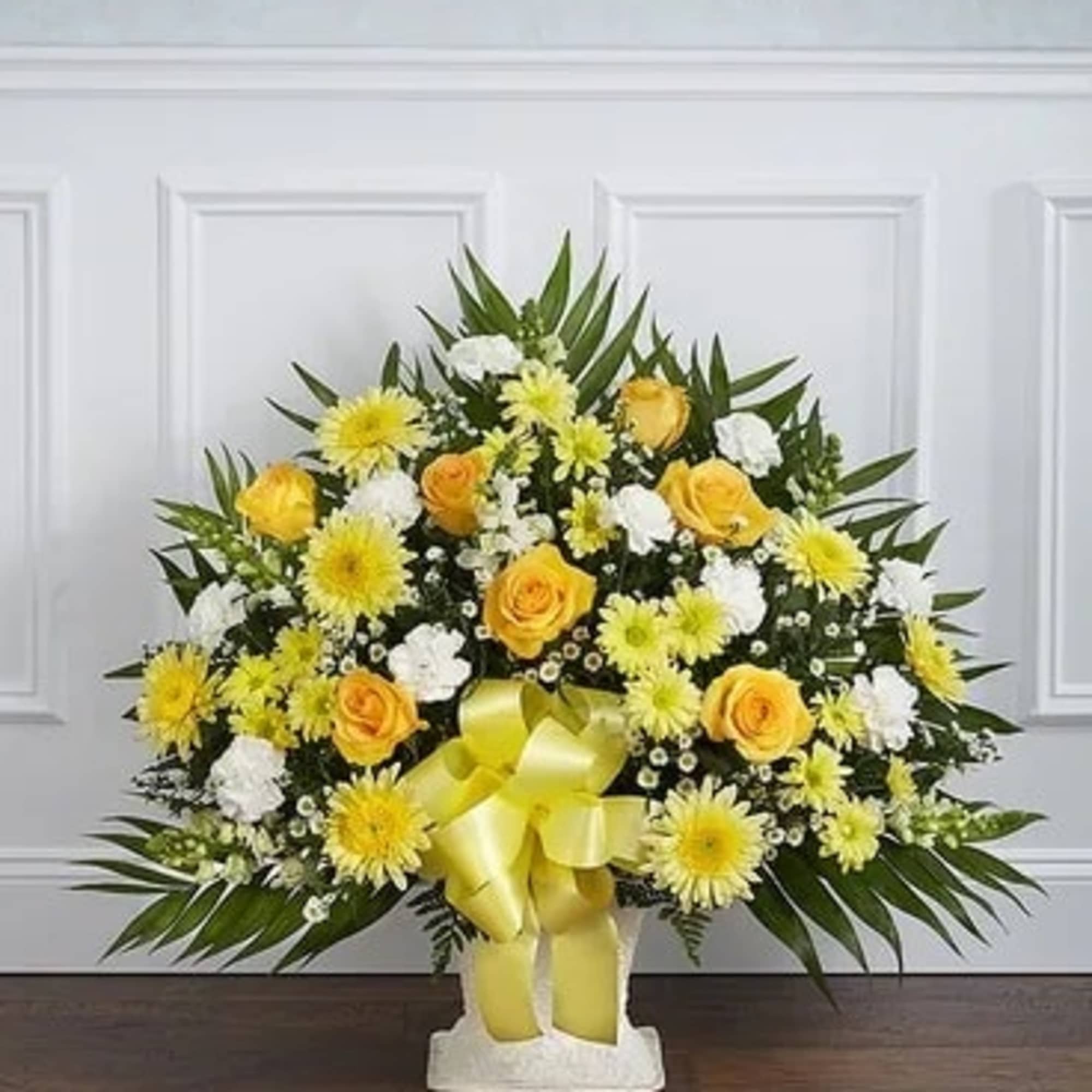 Yellow and white floral spray with a ribbon bow in a white vase