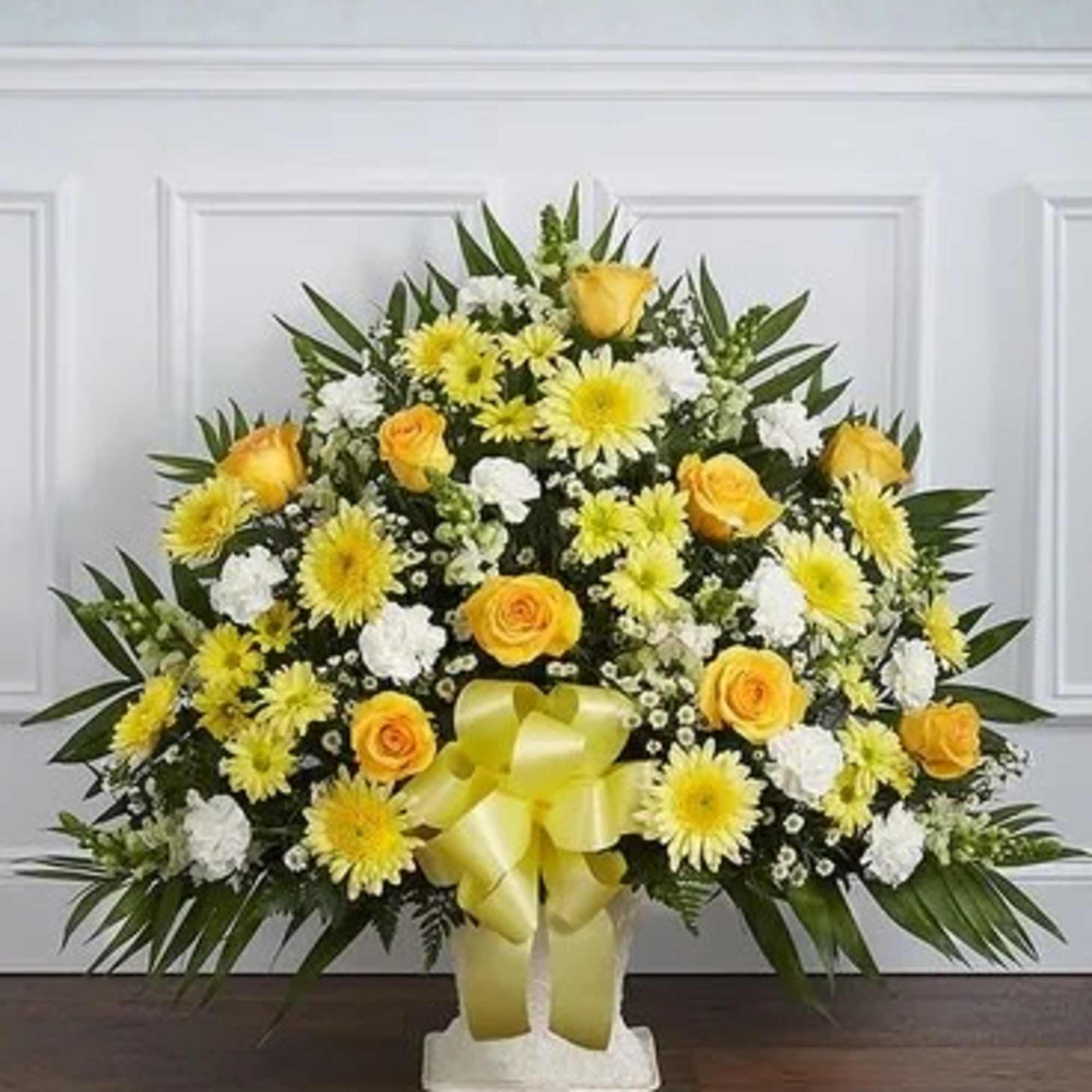 Yellow and white floral standing spray with a ribbon on a white base