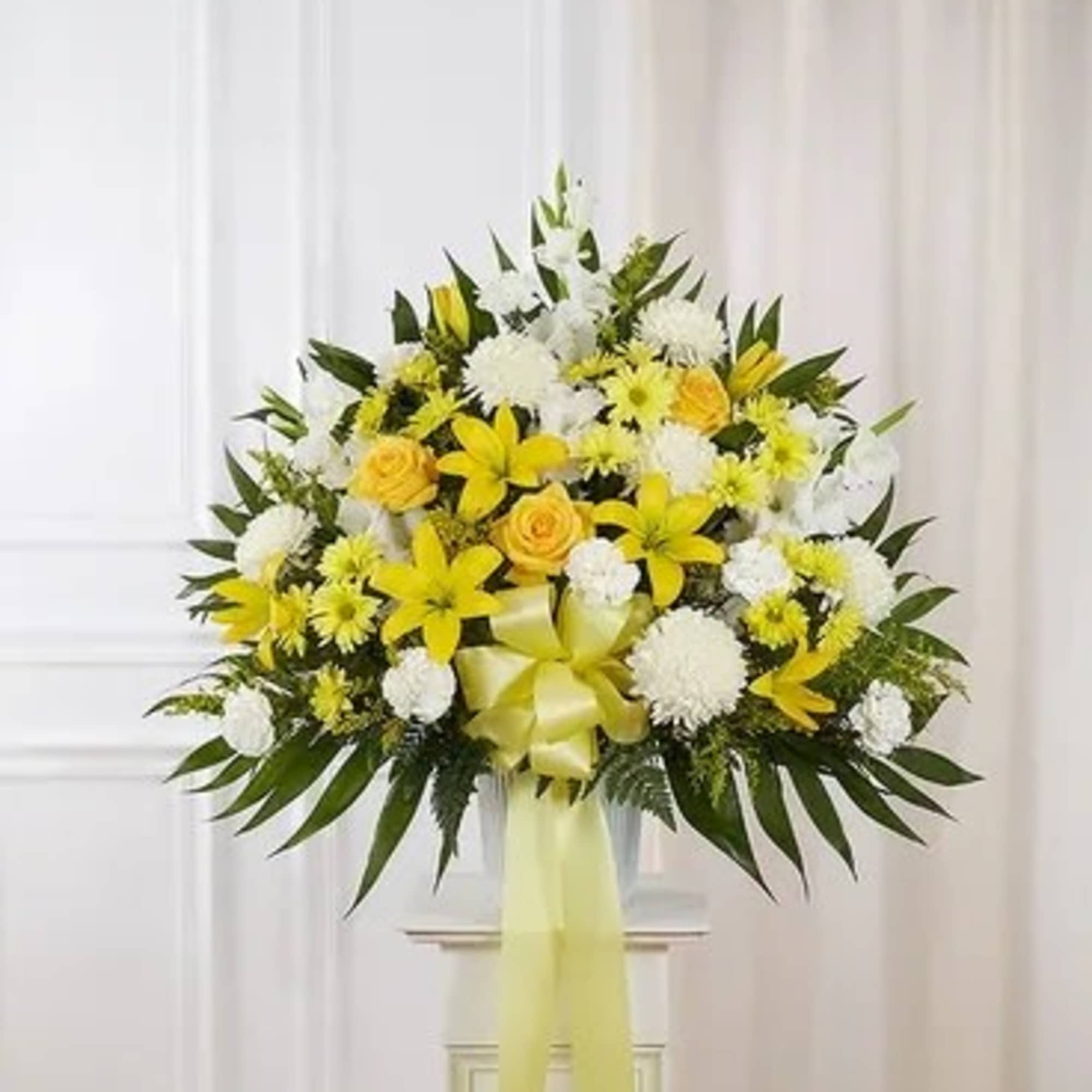 Yellow and white floral standing spray with a ribbon bow
