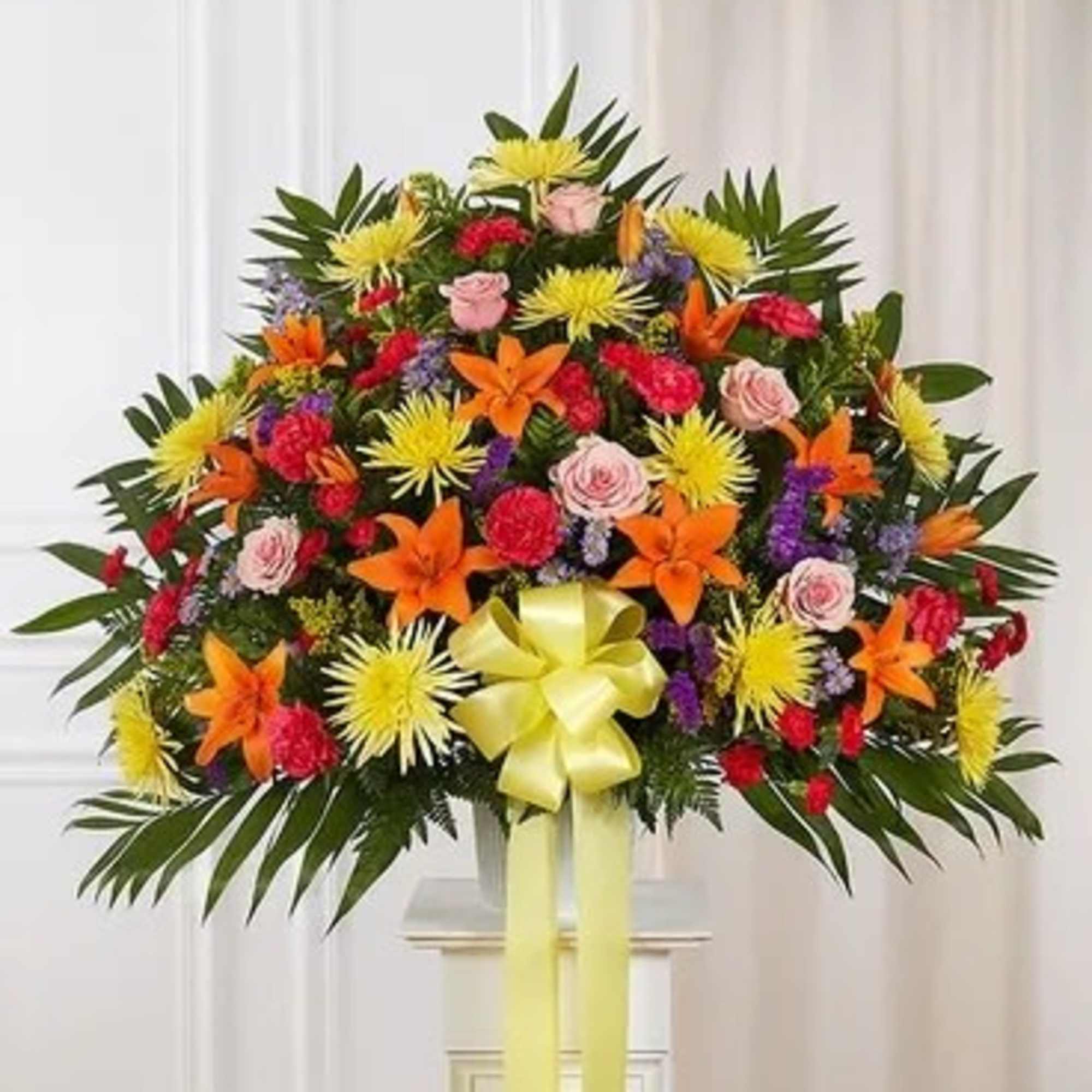 Large standing floral spray with mixed bright flowers and a yellow ribbon