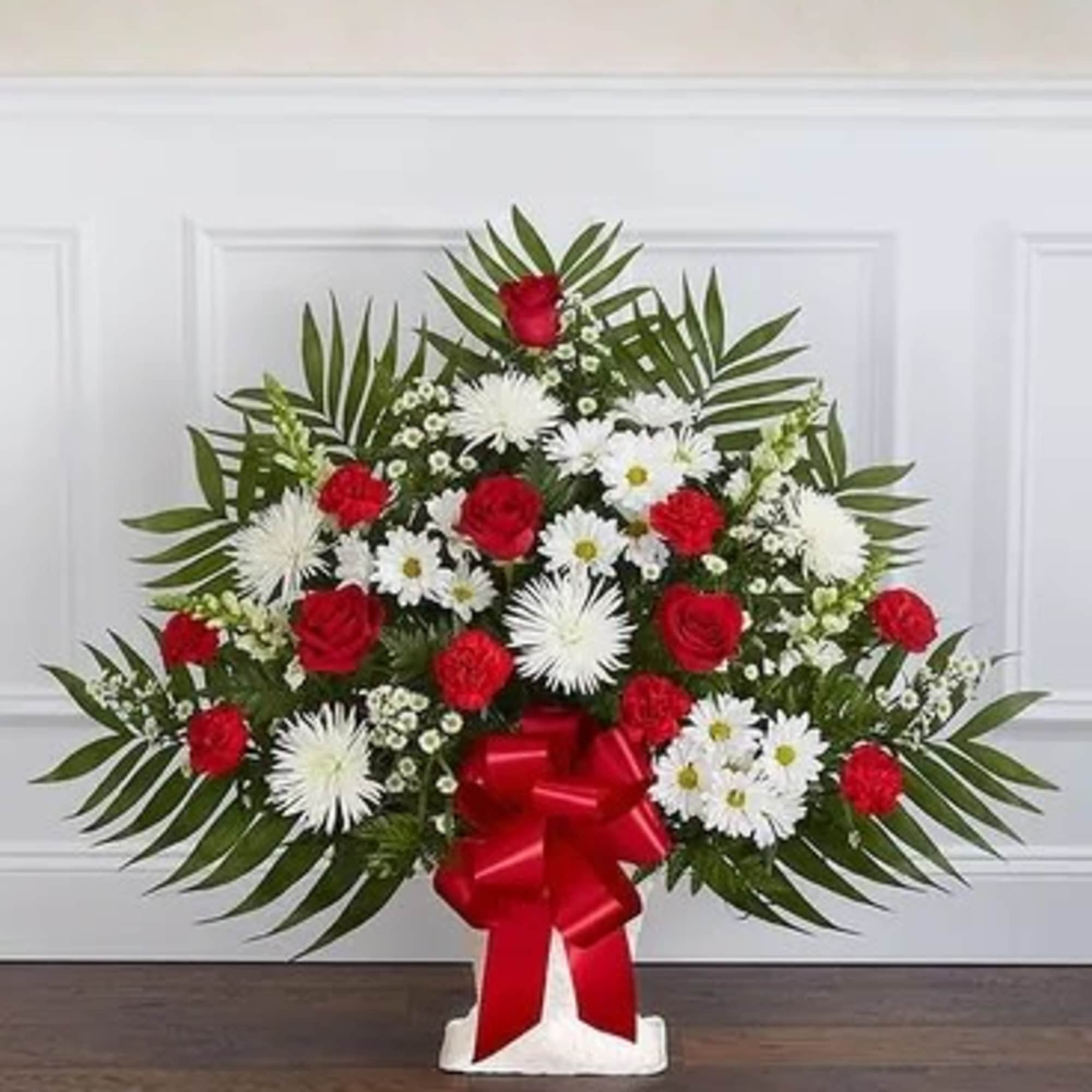 Standing floral spray with red roses and white daisies on a white easel