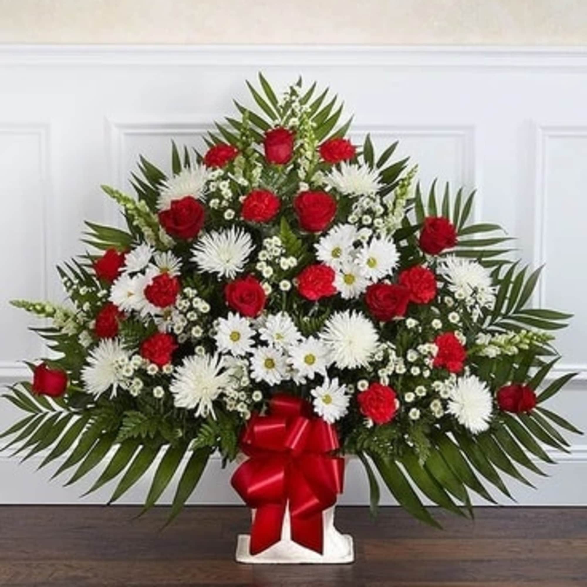 Red roses and white daisies in a standing arrangement with a red bow