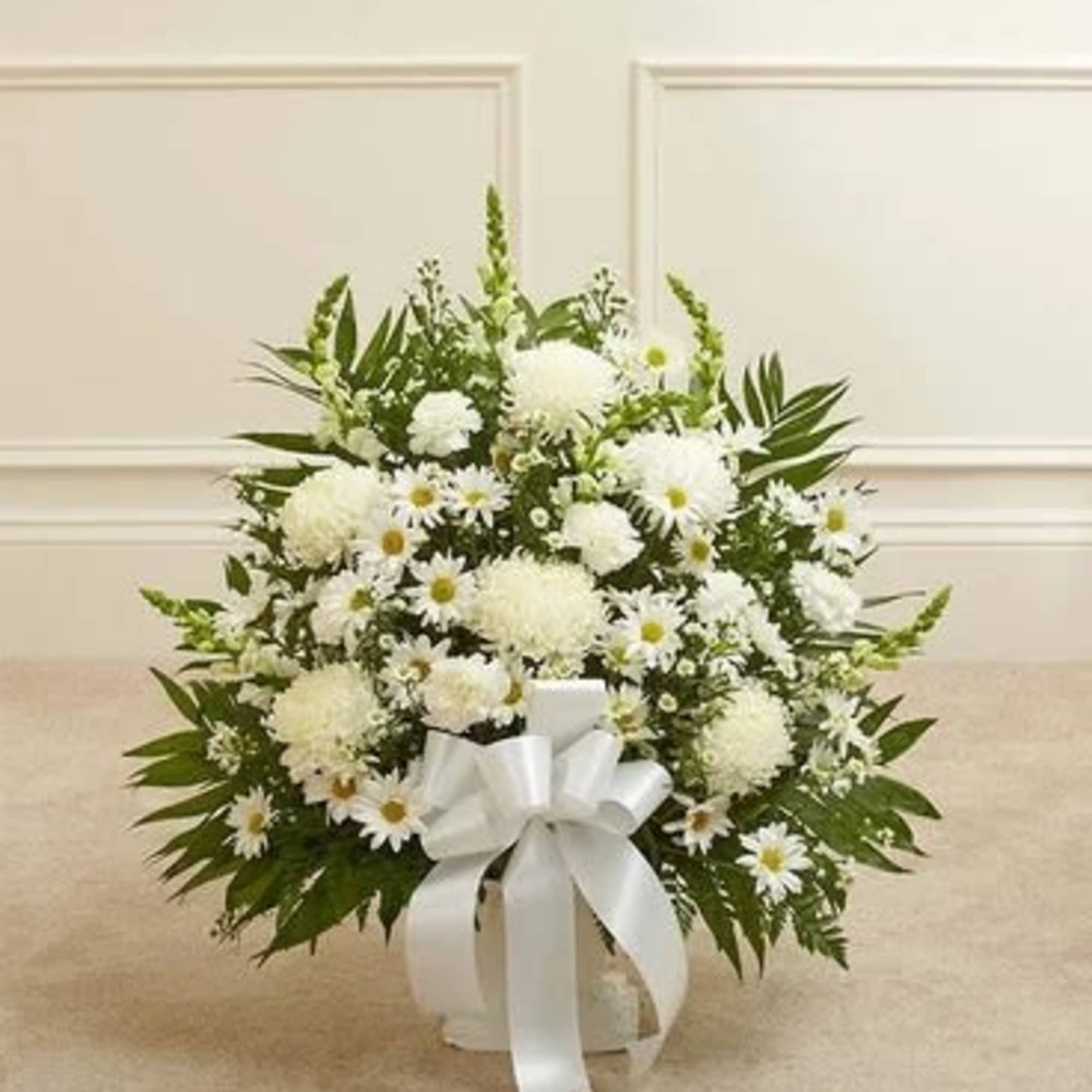 White floral arrangement in a white container with a ribbon bow