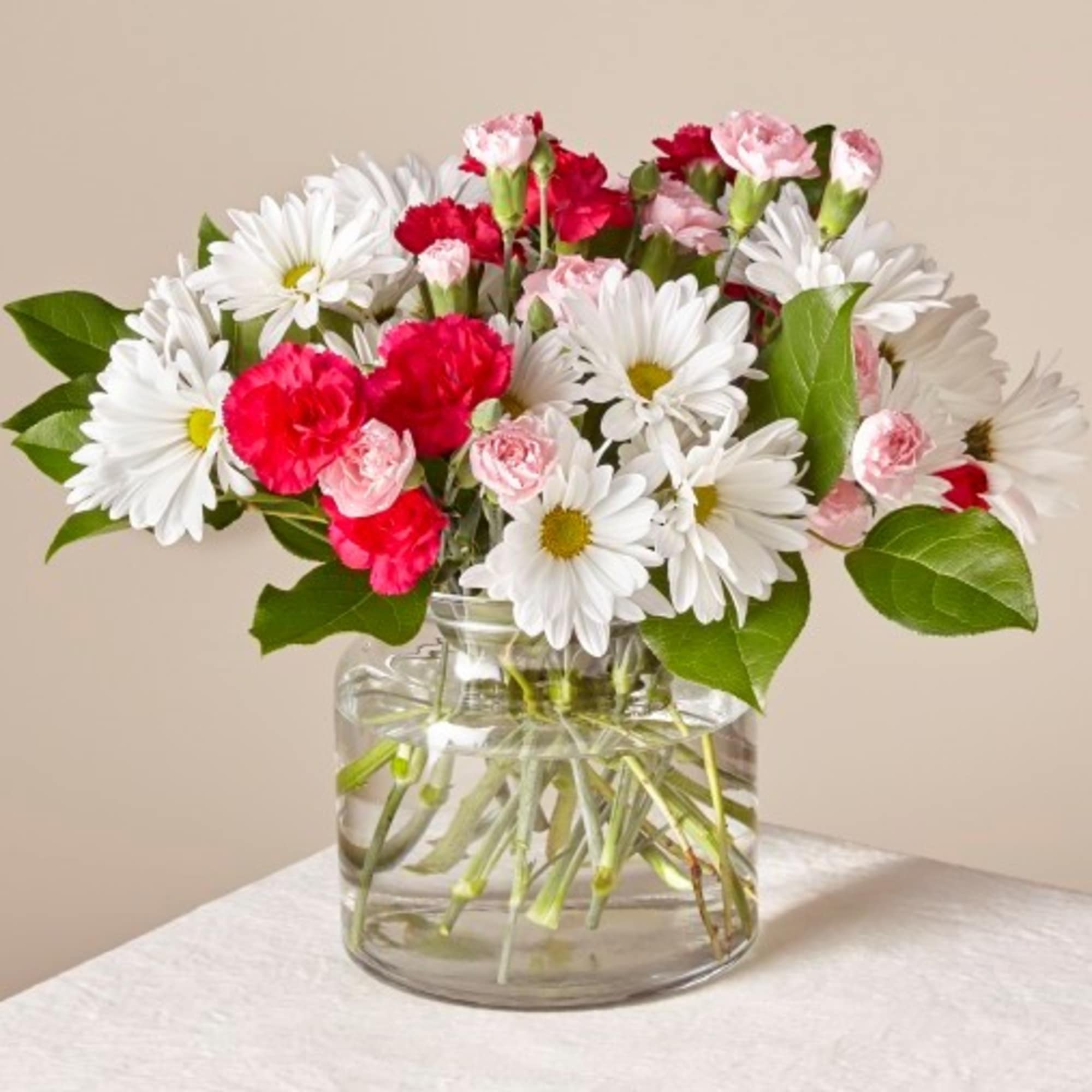 Bouquet of white daisies and pink carnations in a clear glass vase