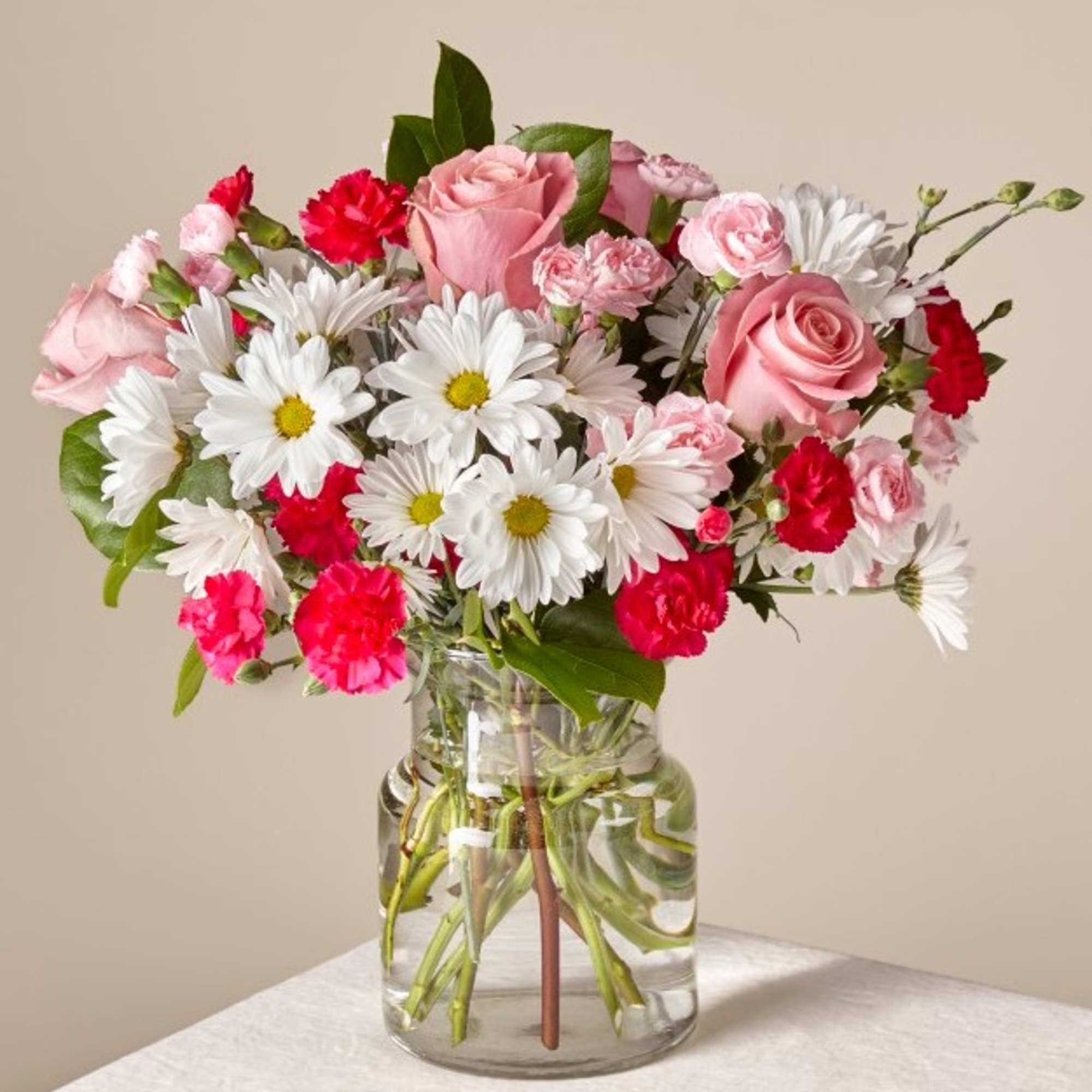 Pink roses, white daisies, and red carnations in a glass vase