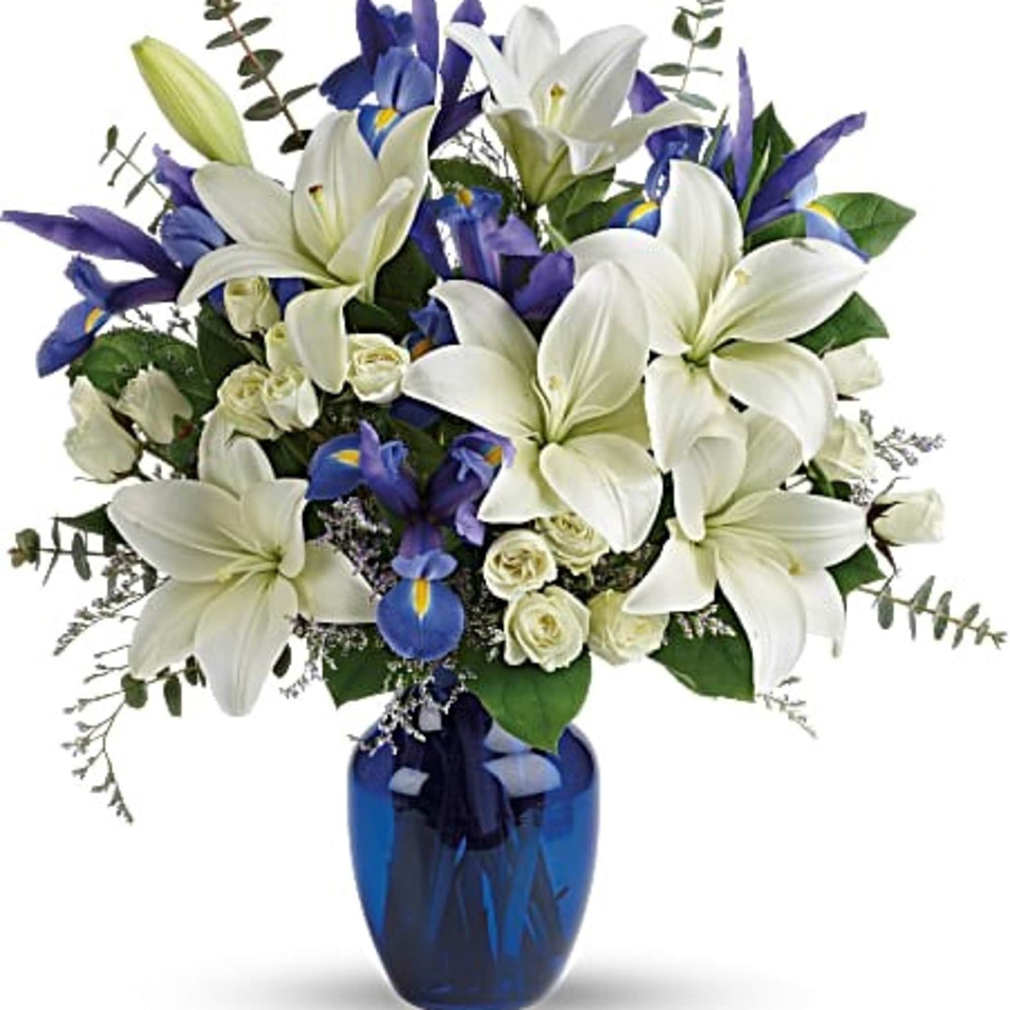 White lilies and blue irises arranged in a blue glass vase