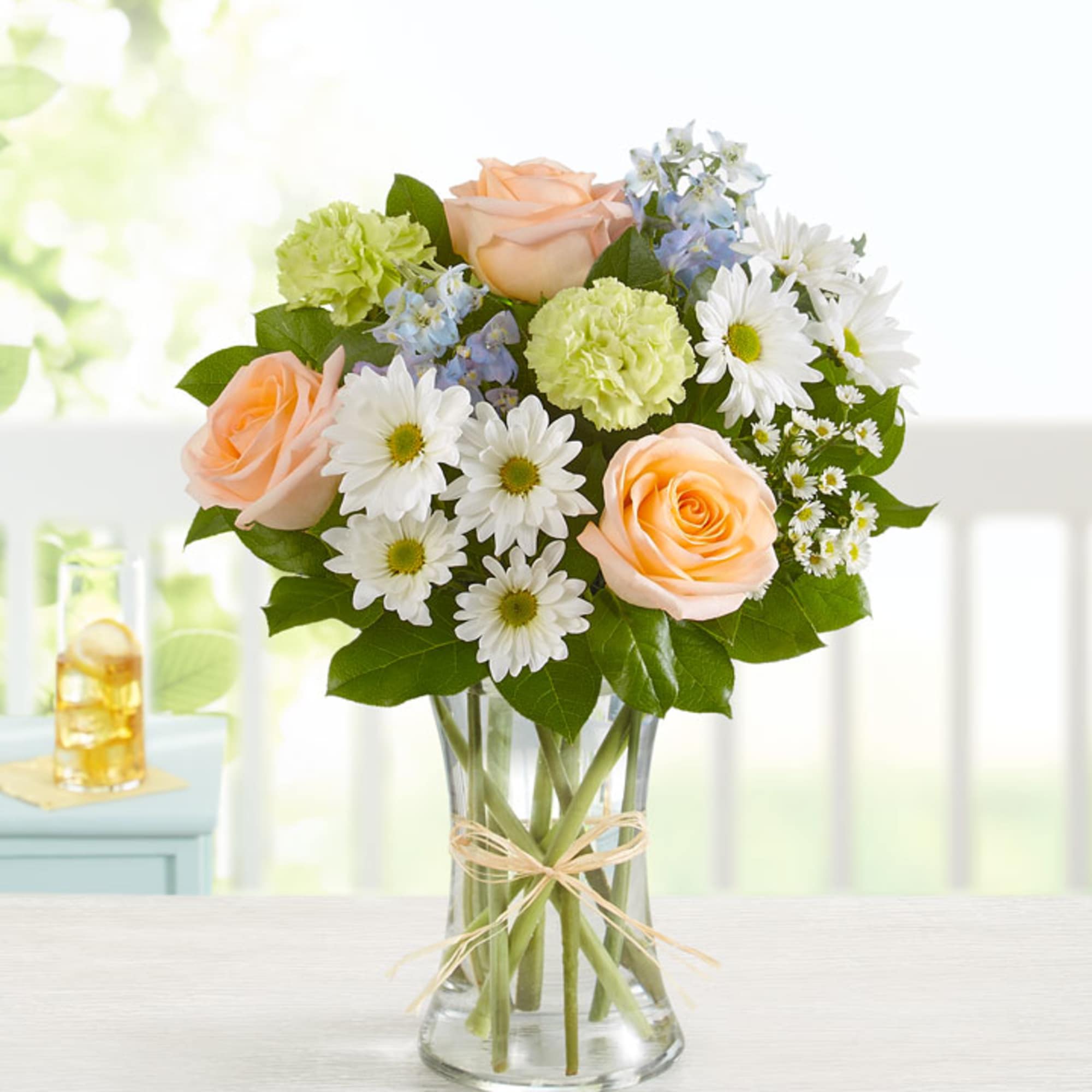 Peach roses and white daisies in a clear glass vase