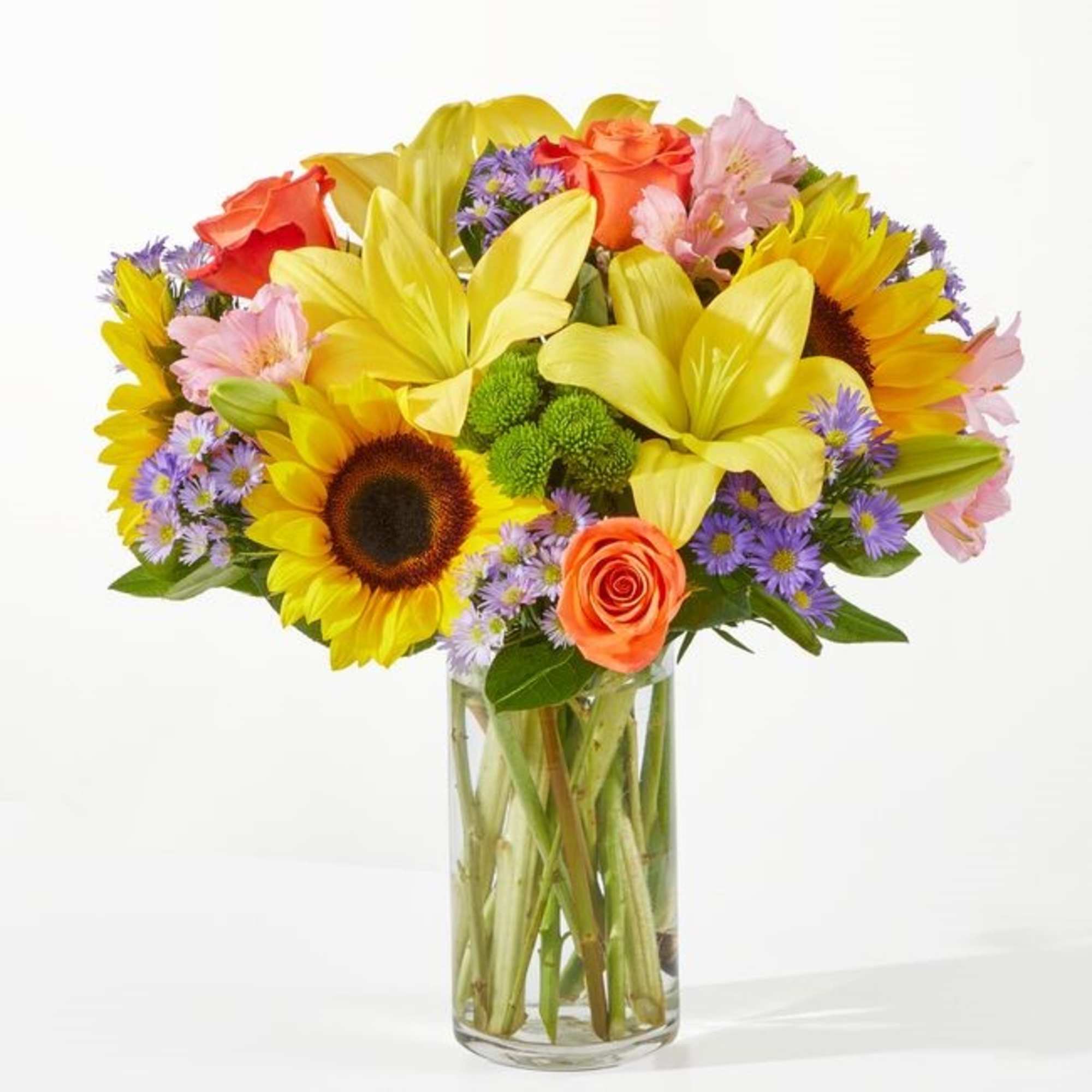 Mixed bouquet of sunflowers, lilies, roses, and daisies in a glass vase
