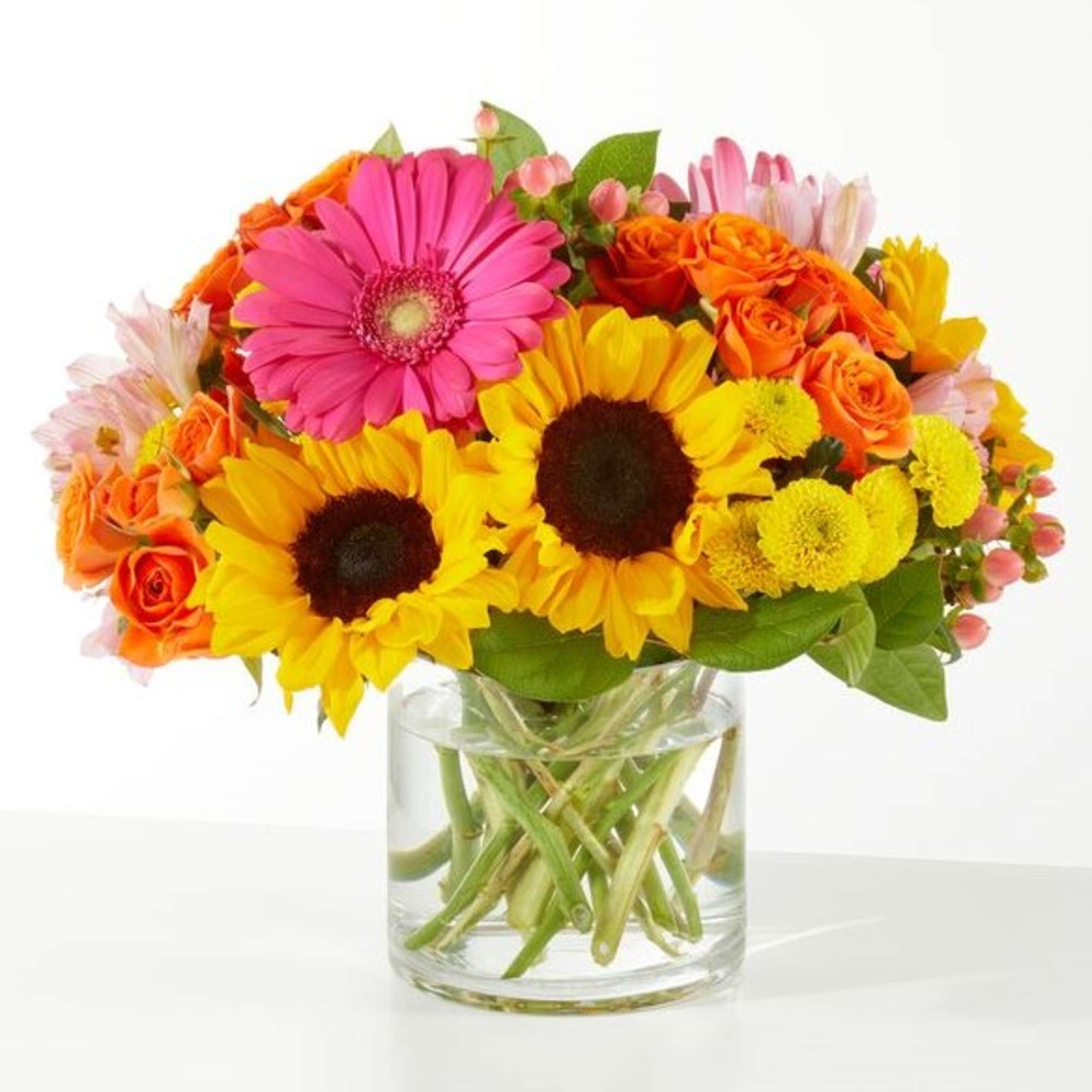 Bright mixed bouquet with sunflowers, gerbera daisies, and orange roses in a glass vase