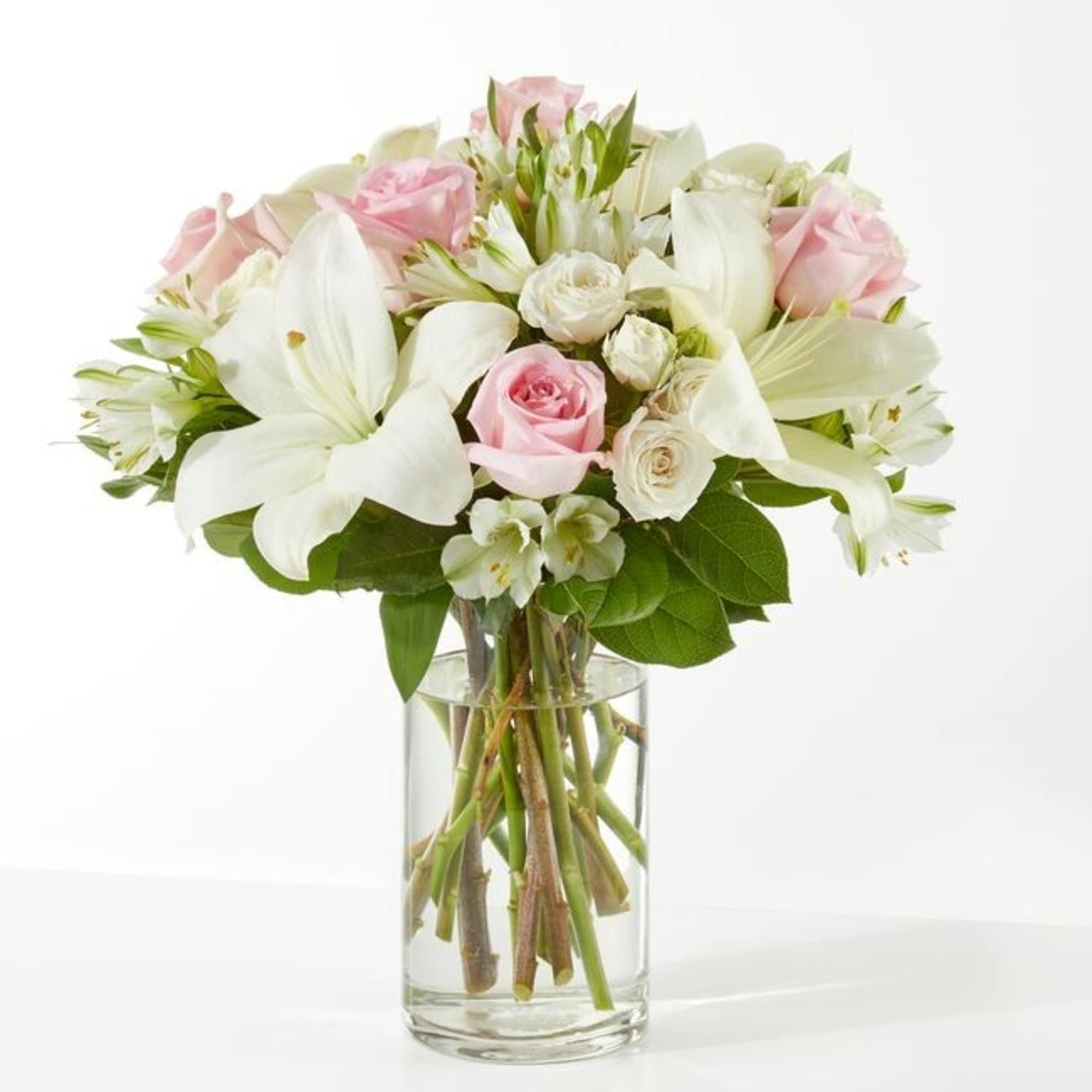 Pink and white bouquet of roses and lilies in a clear glass vase