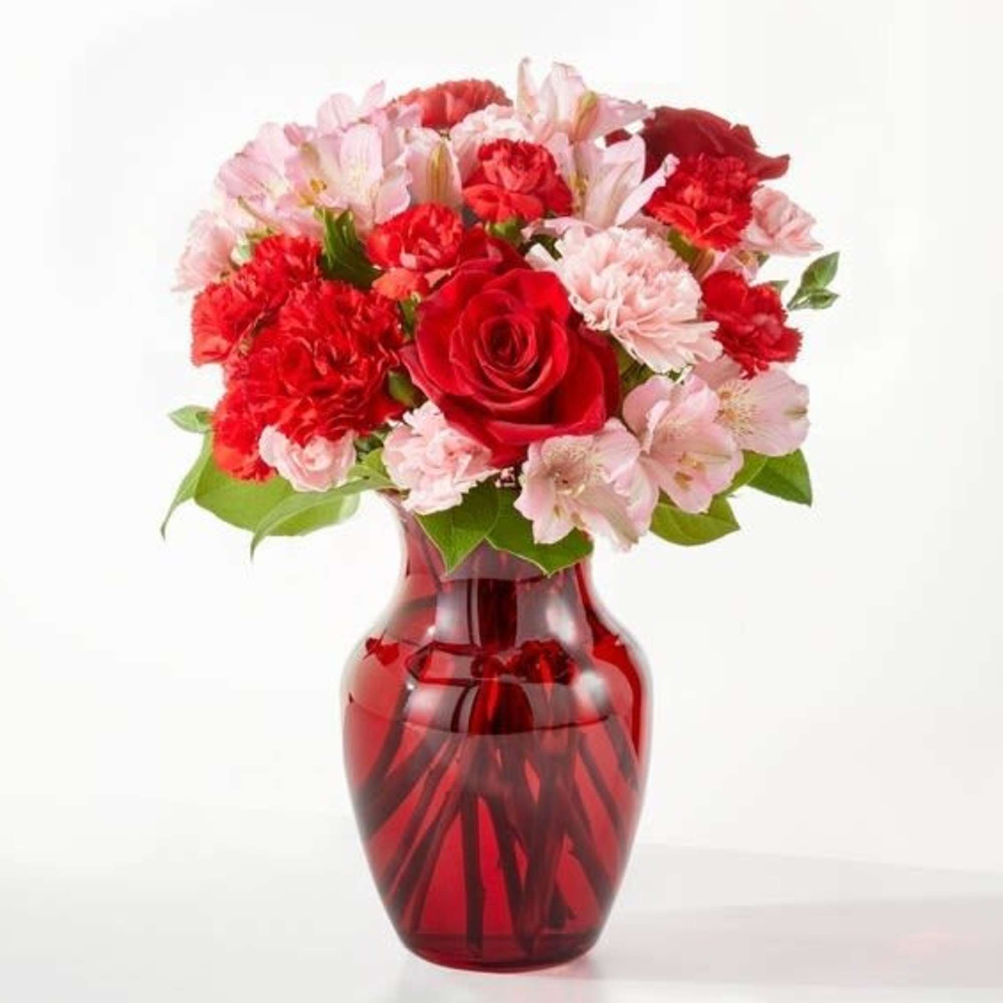 Red and pink flower bouquet in a red glass vase