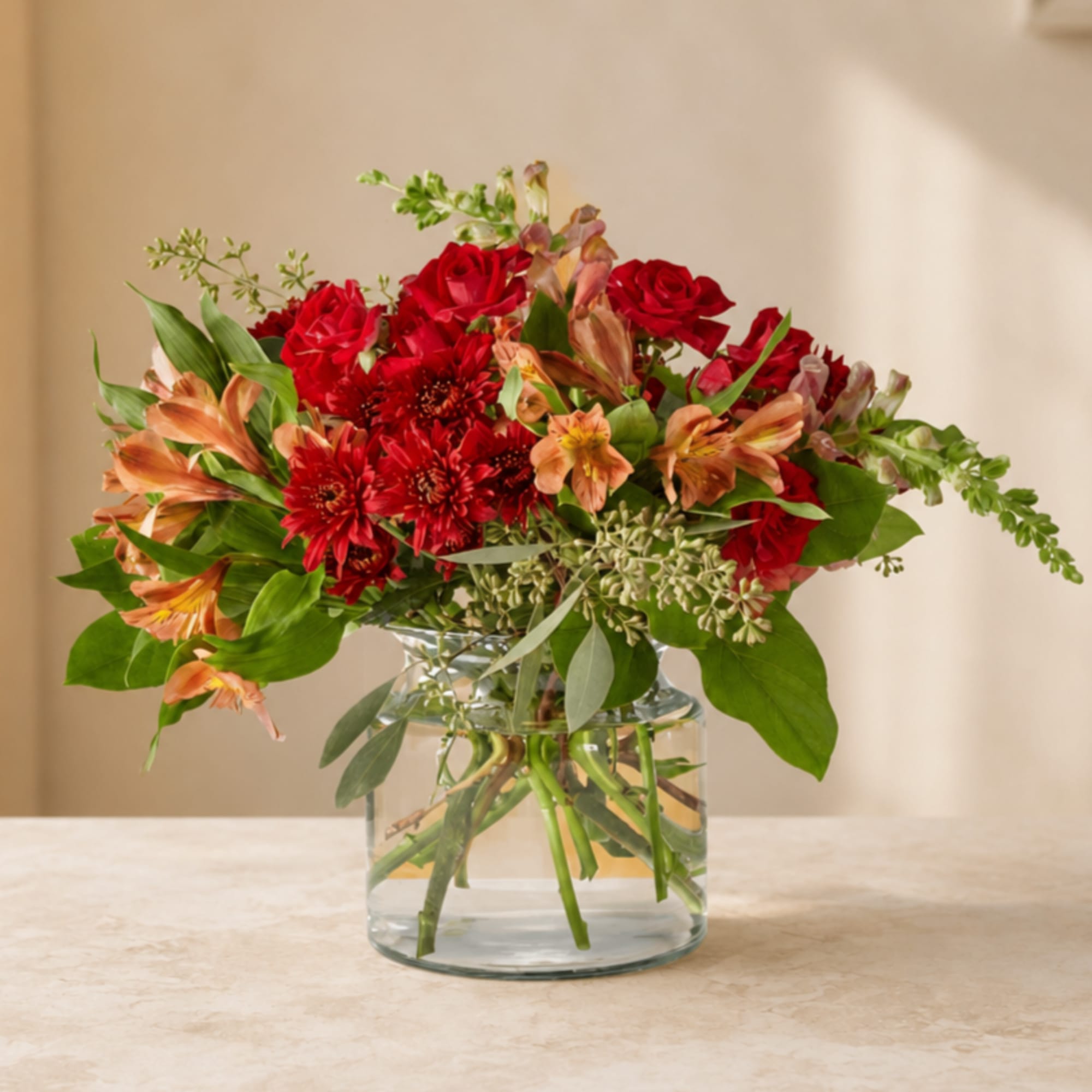 Red roses and orange alstroemeria in a clear glass vase