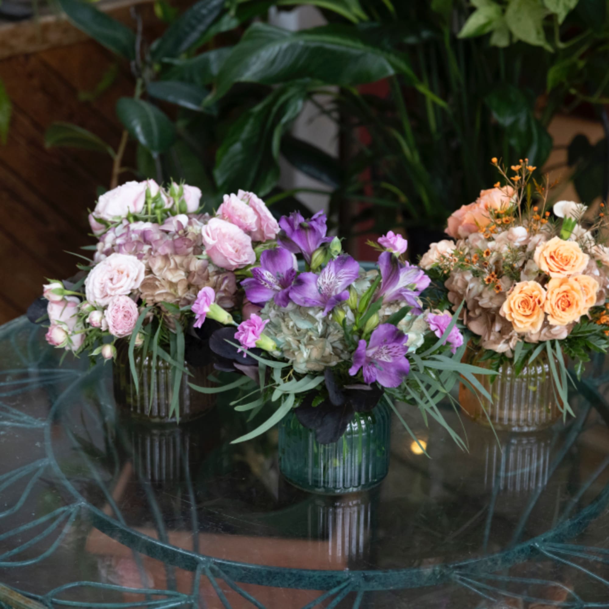 Three floral arrangements in glass vases on a table