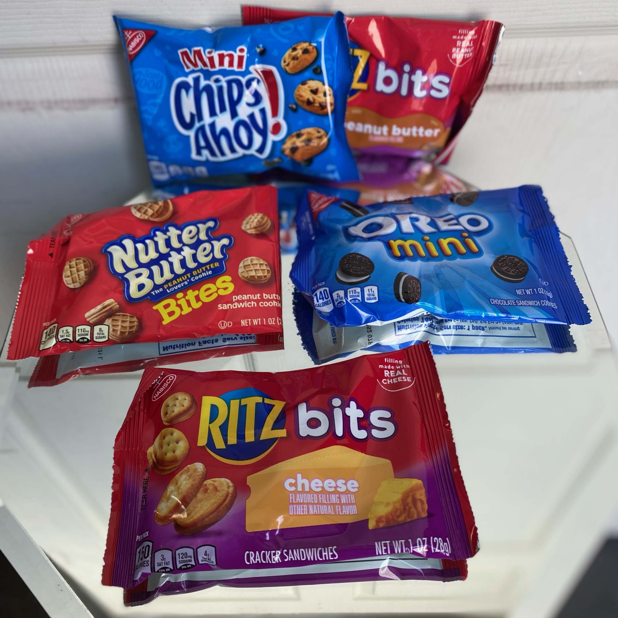 Assorted snack packs of cookies and cracker bites on a white surface