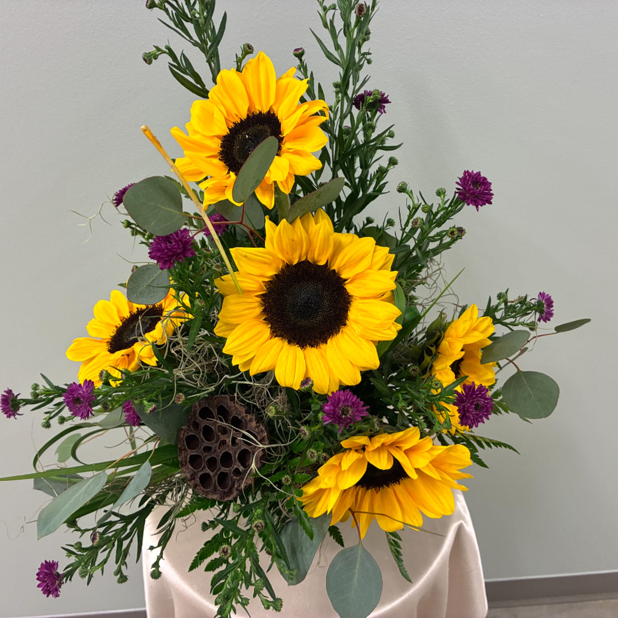 Sunflower arrangement with purple accent flowers in a vase