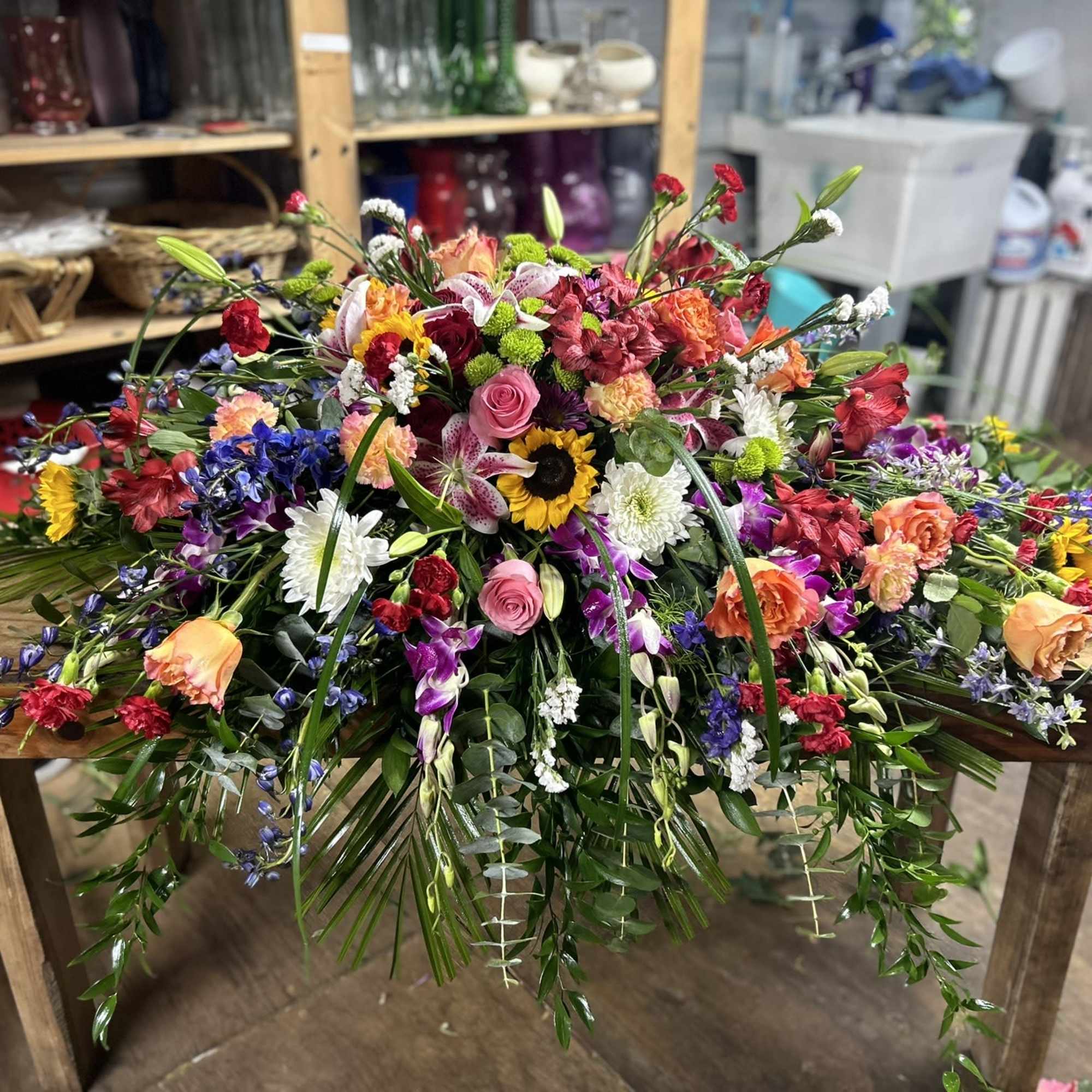 Large multicolored spray of mixed flowers cascading across a wooden table.