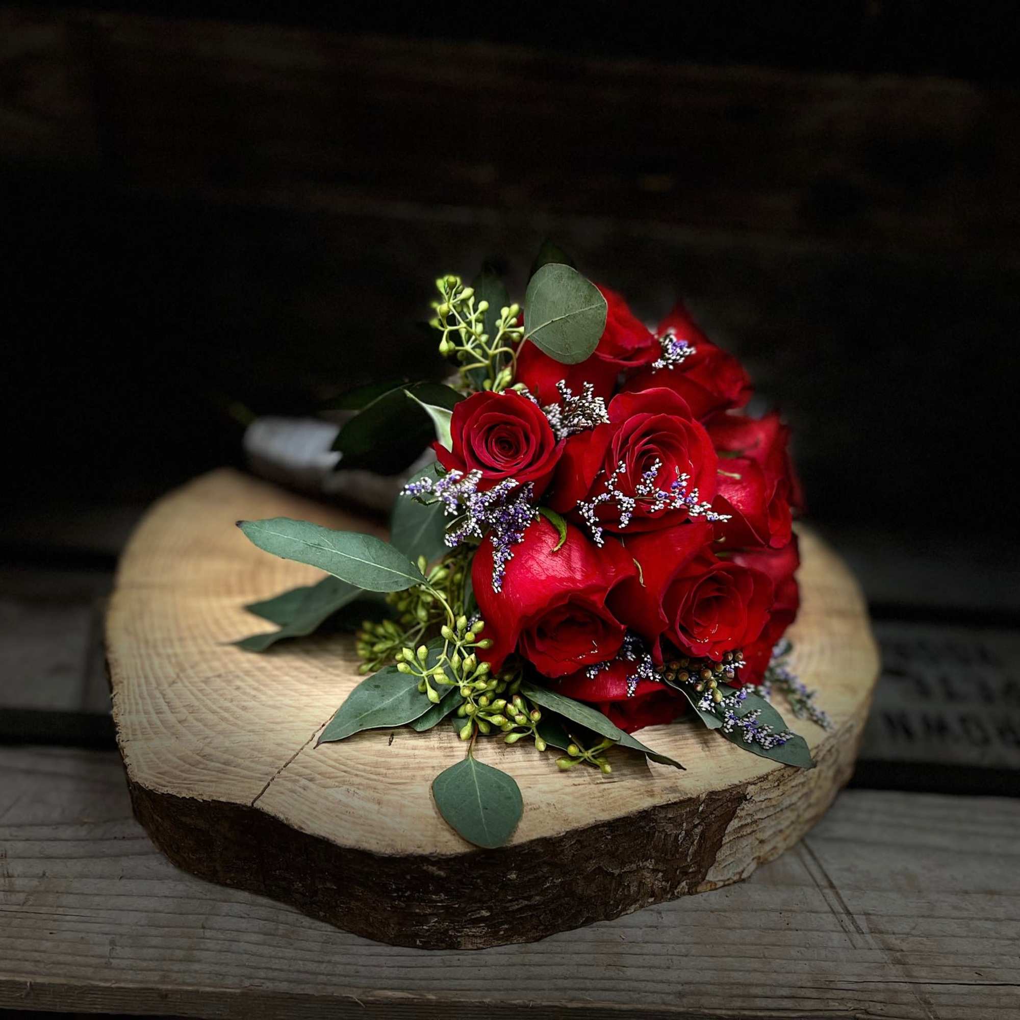 Red rose bouquet with eucalyptus on a wood slice